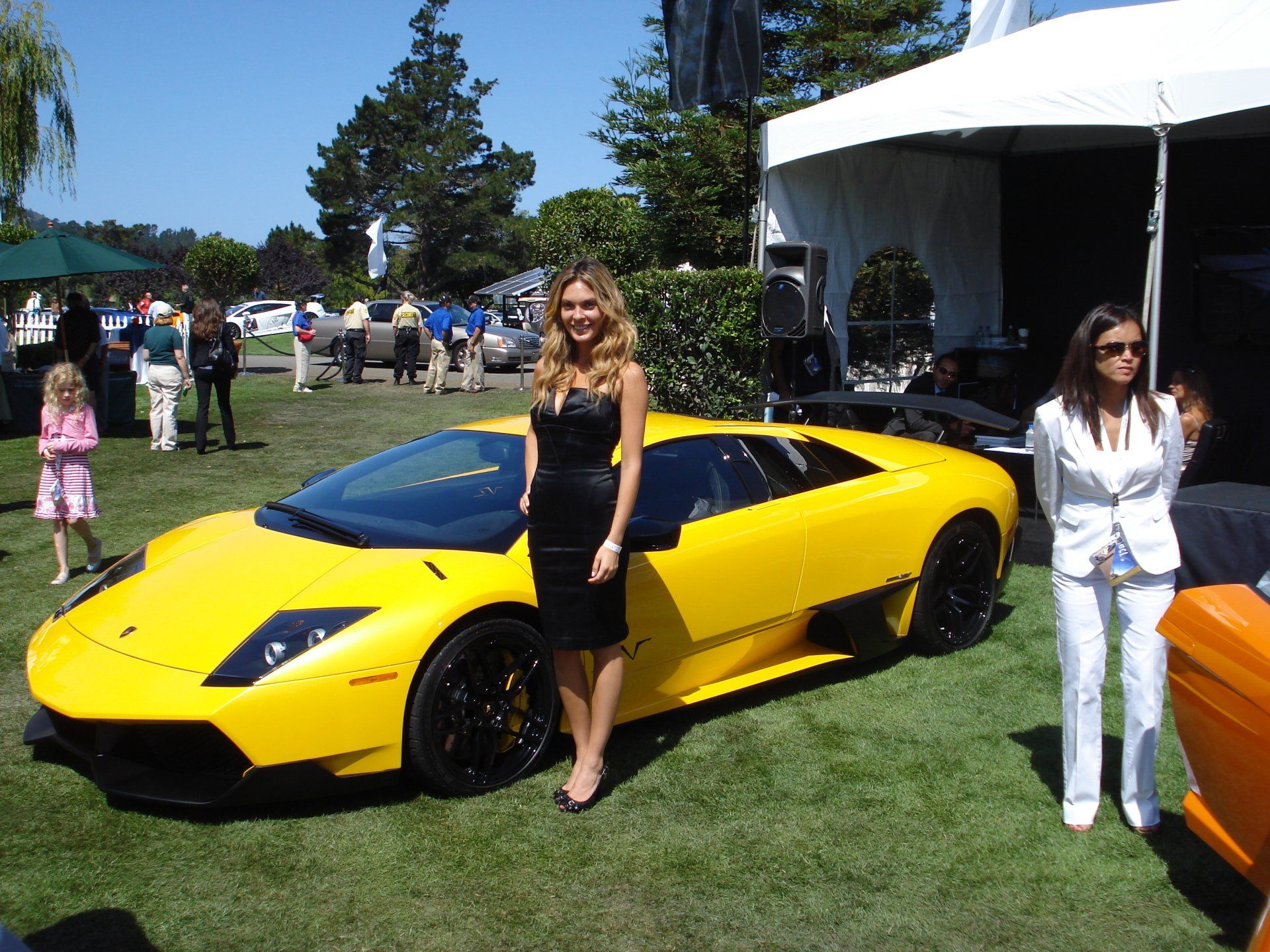 Two women standing in front of a yellow sports car