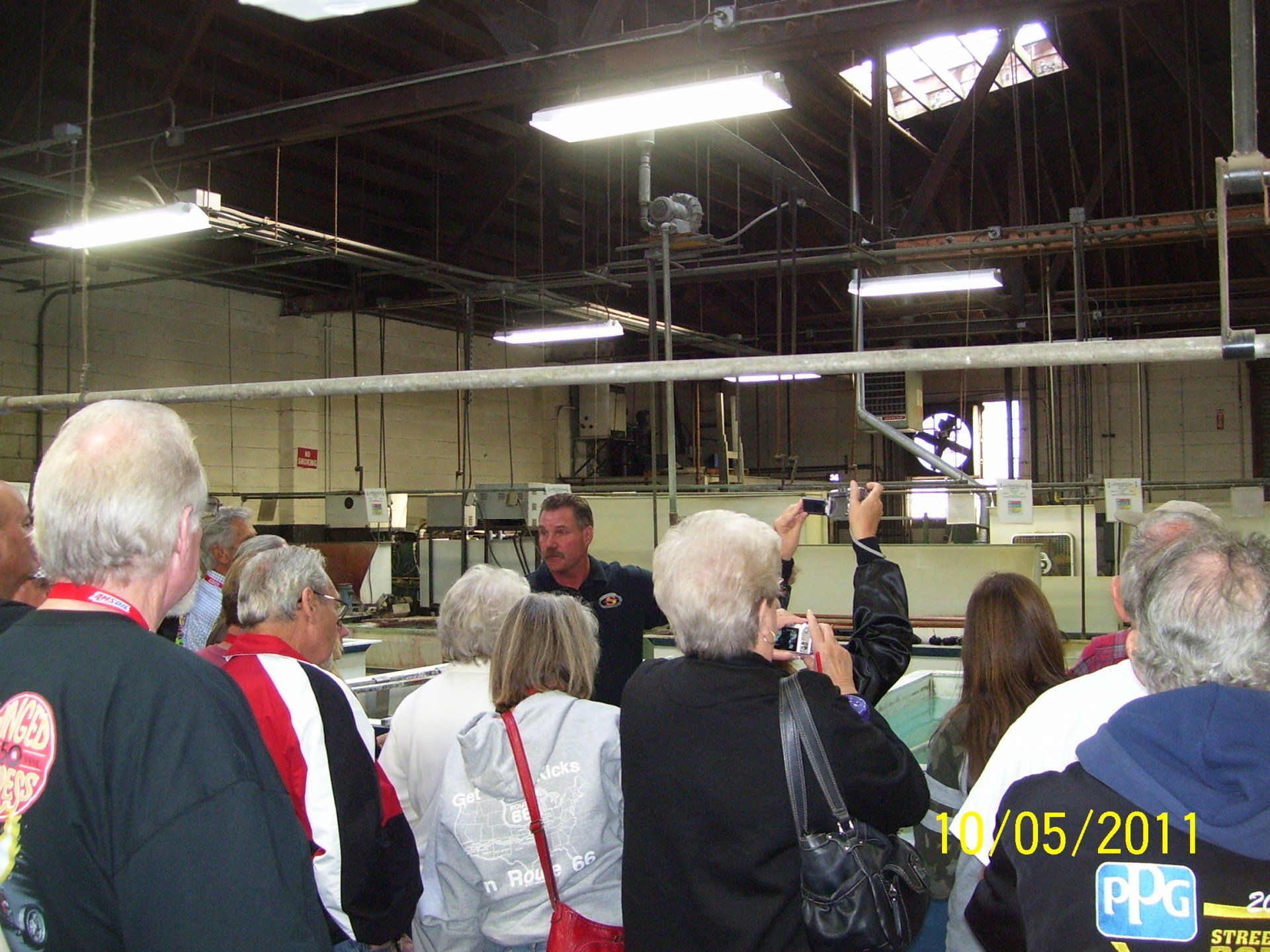 A group of people are gathered in a room with a man giving a presentation