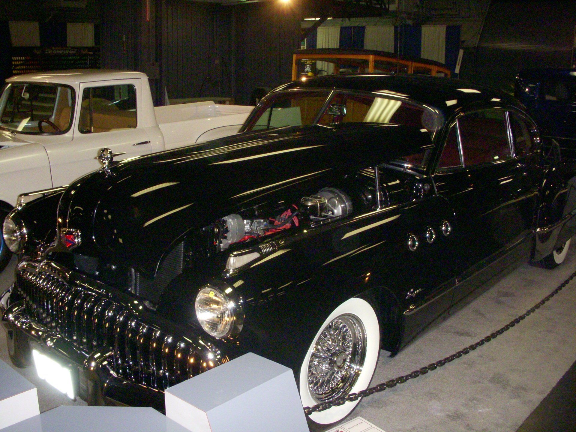 A black car with white tires is parked next to a white truck