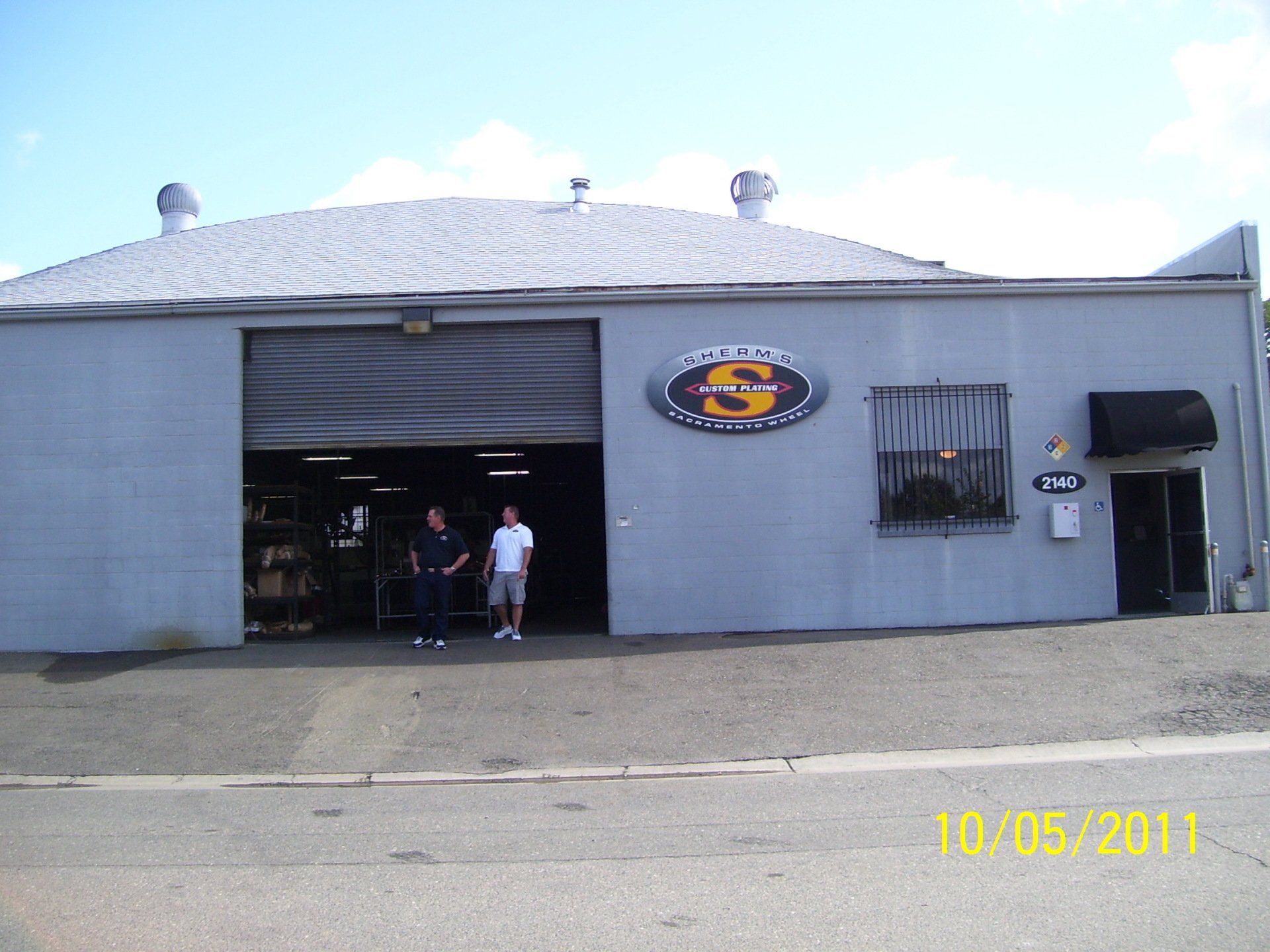 Two men standing in front of a building that has the letter s on it