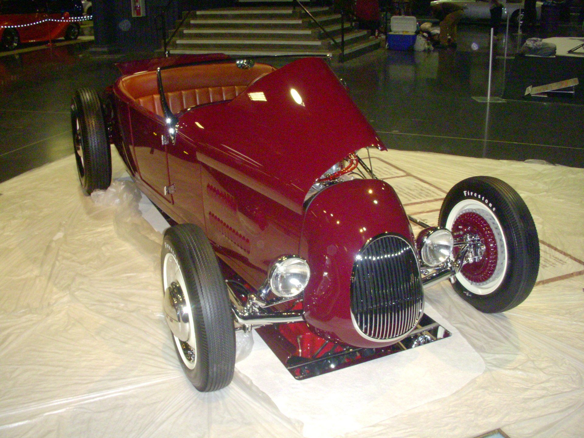 A red car with the hood up is on display