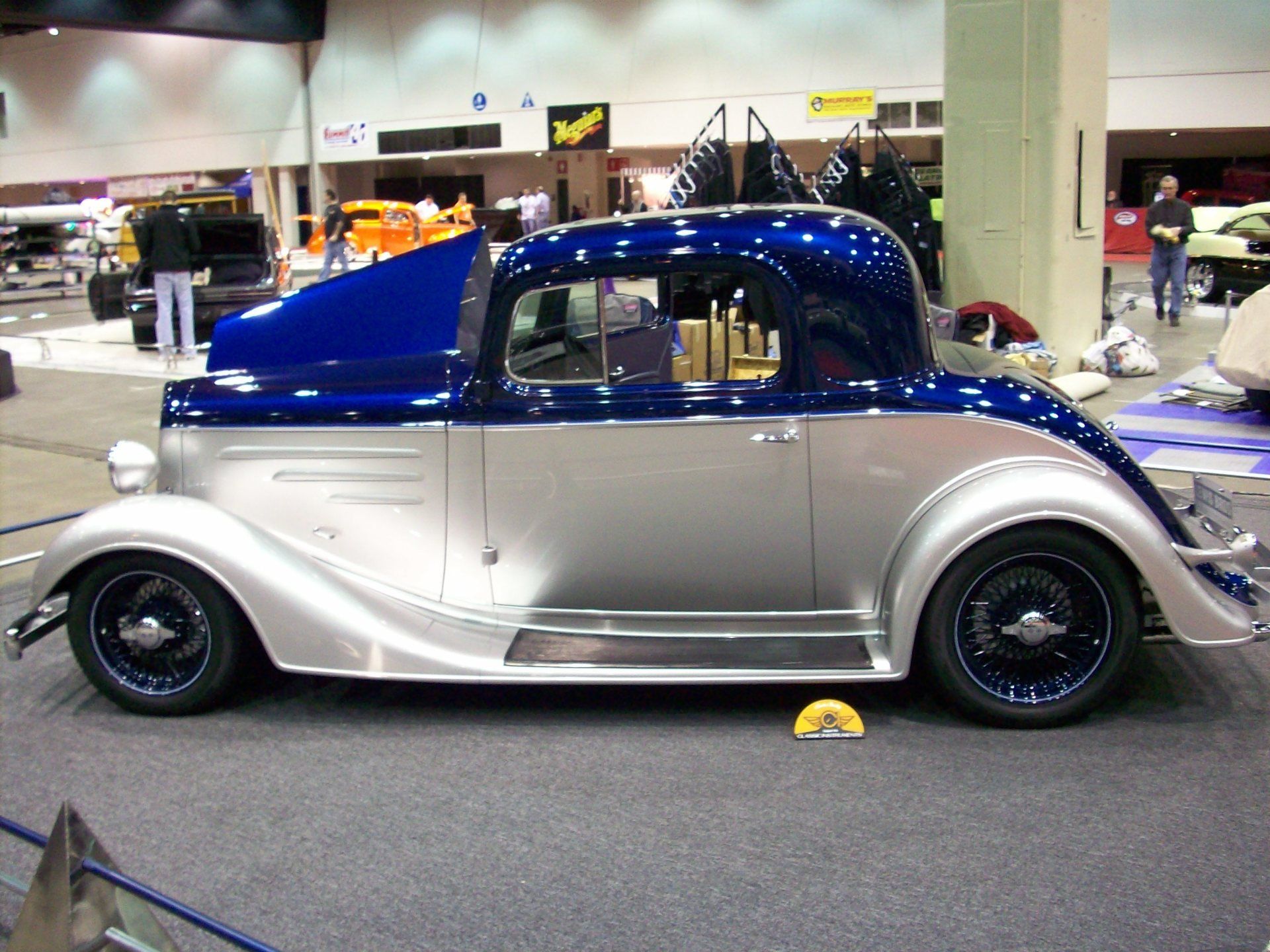 A silver and blue car is on display at a car show