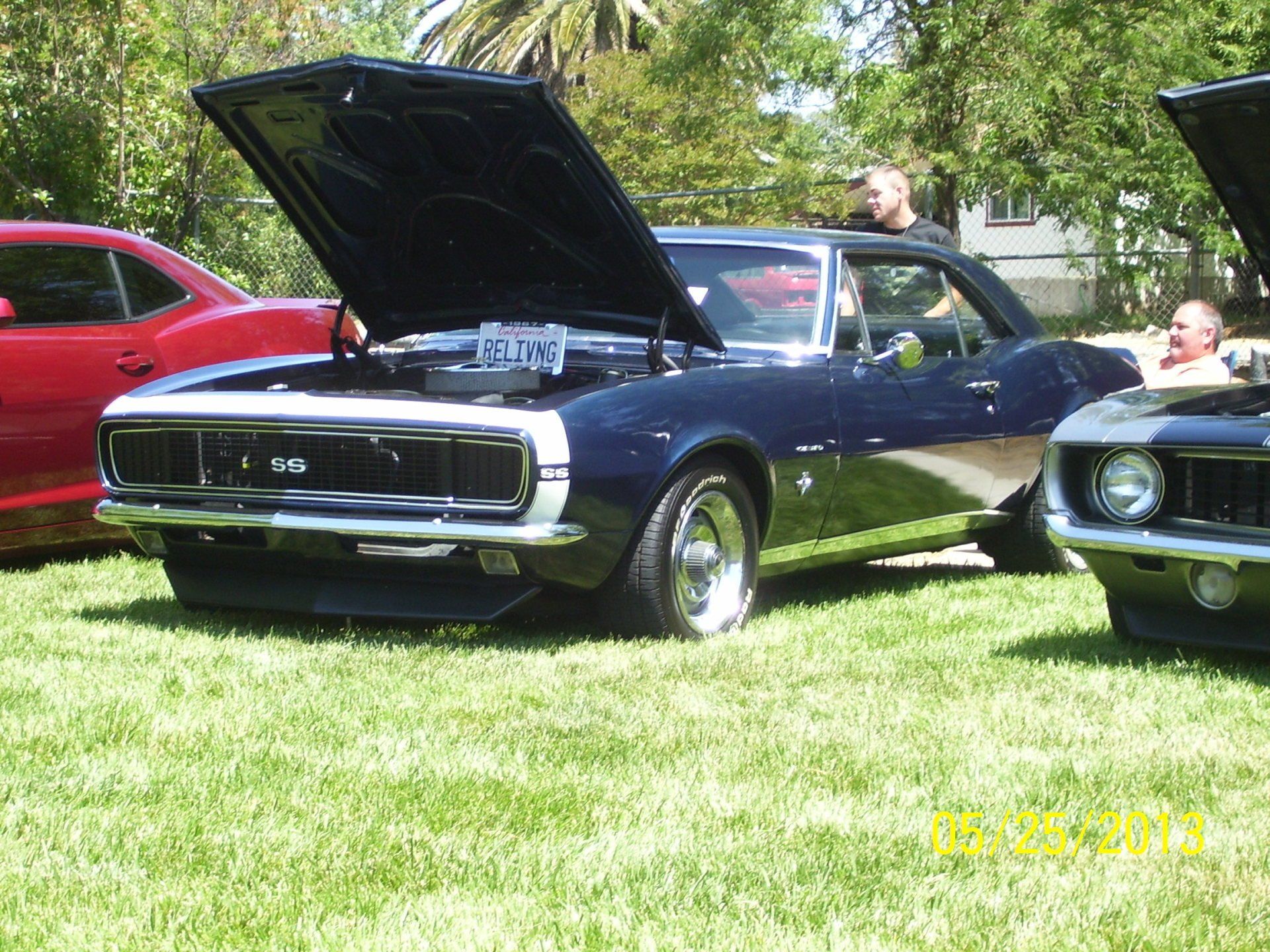 A black car with the hood up is parked next to a red car