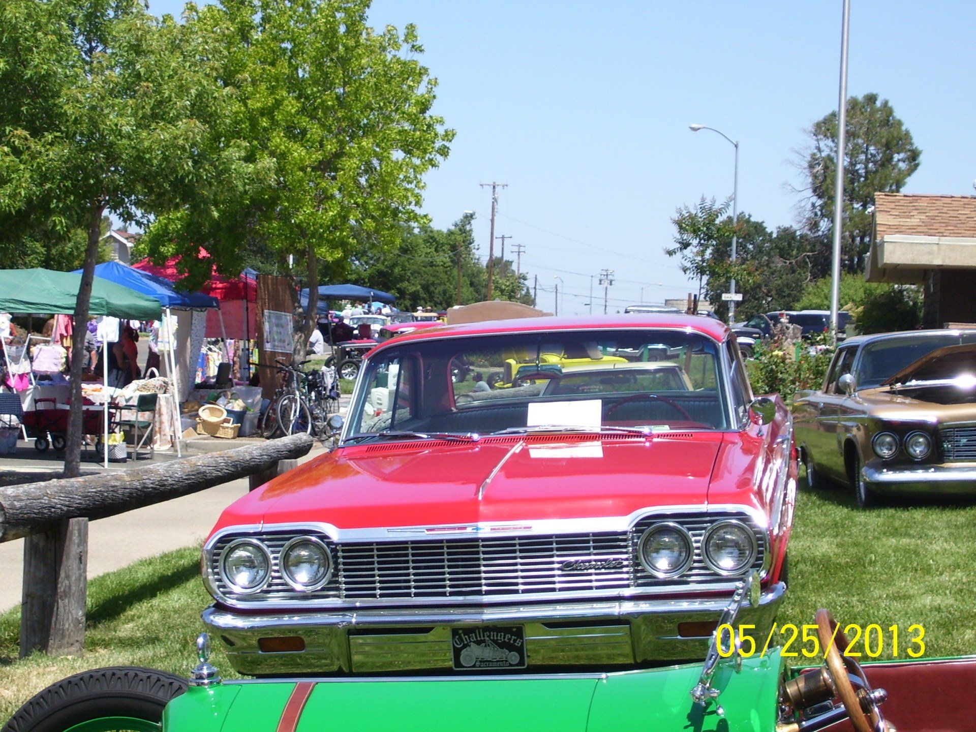 A red car is parked next to a green car at a car show
