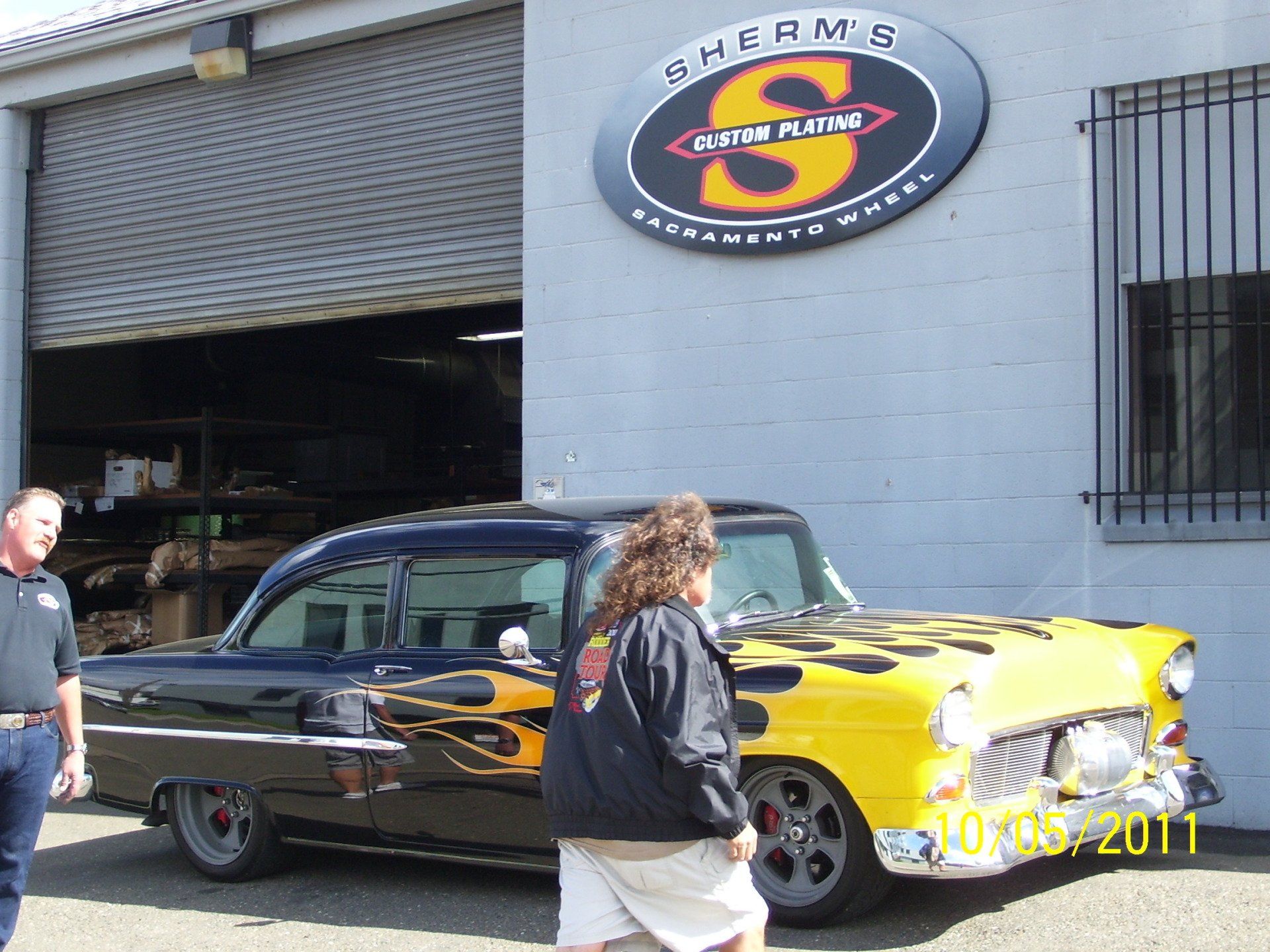A yellow car is parked in front of a store called sherms