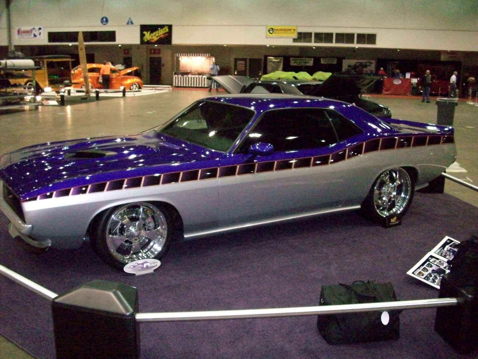 A purple and silver car is on display at a car show