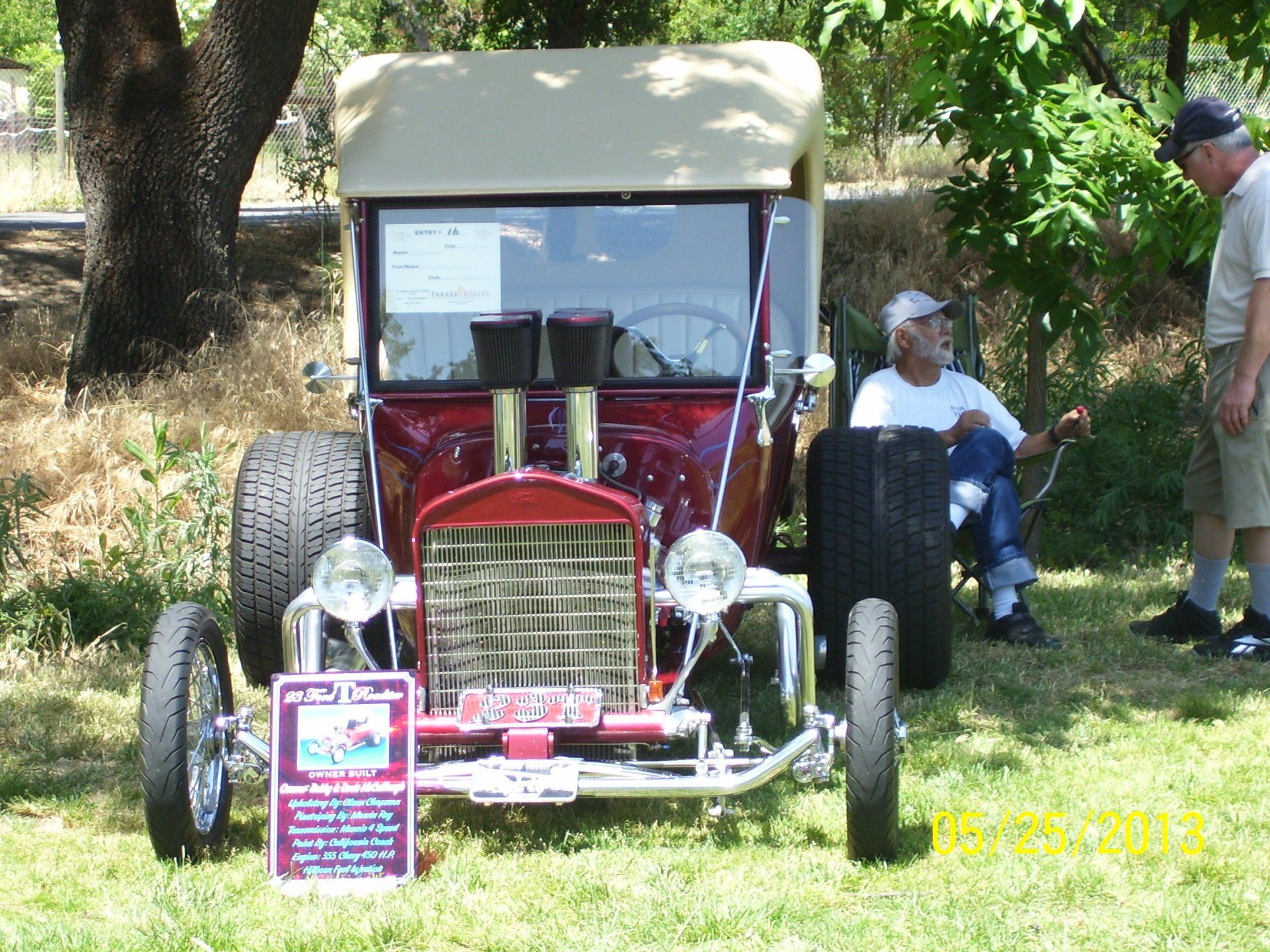 A man sits in a chair next to a red hot rod