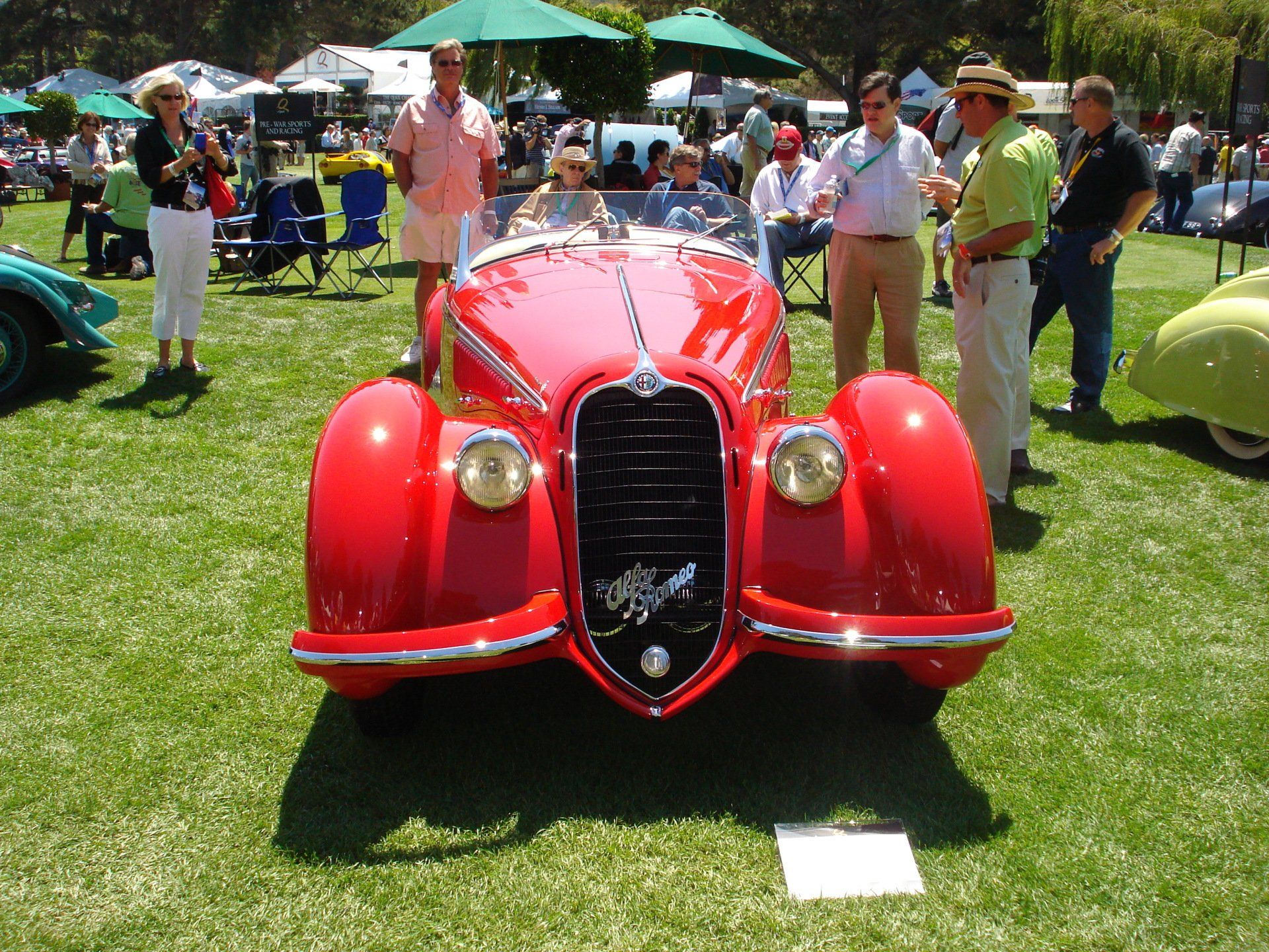 A group of people standing around a red car