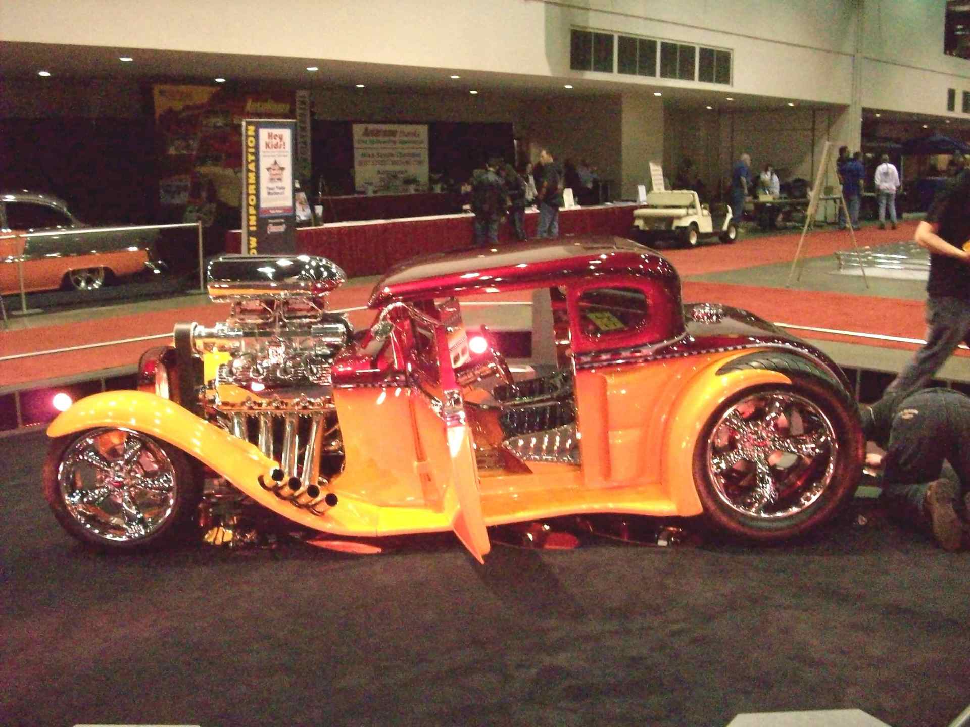 A red and yellow hot rod is on display at a car show