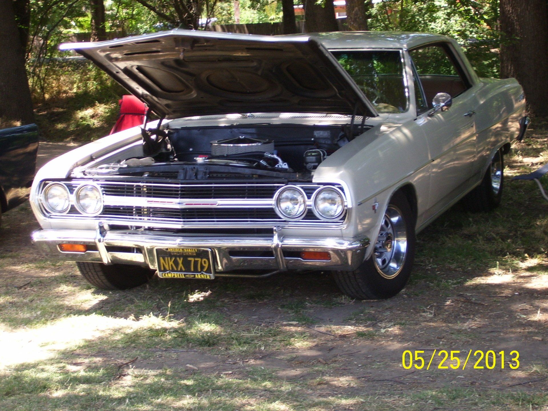 A white car with the hood up has a license plate that says kk3 t79