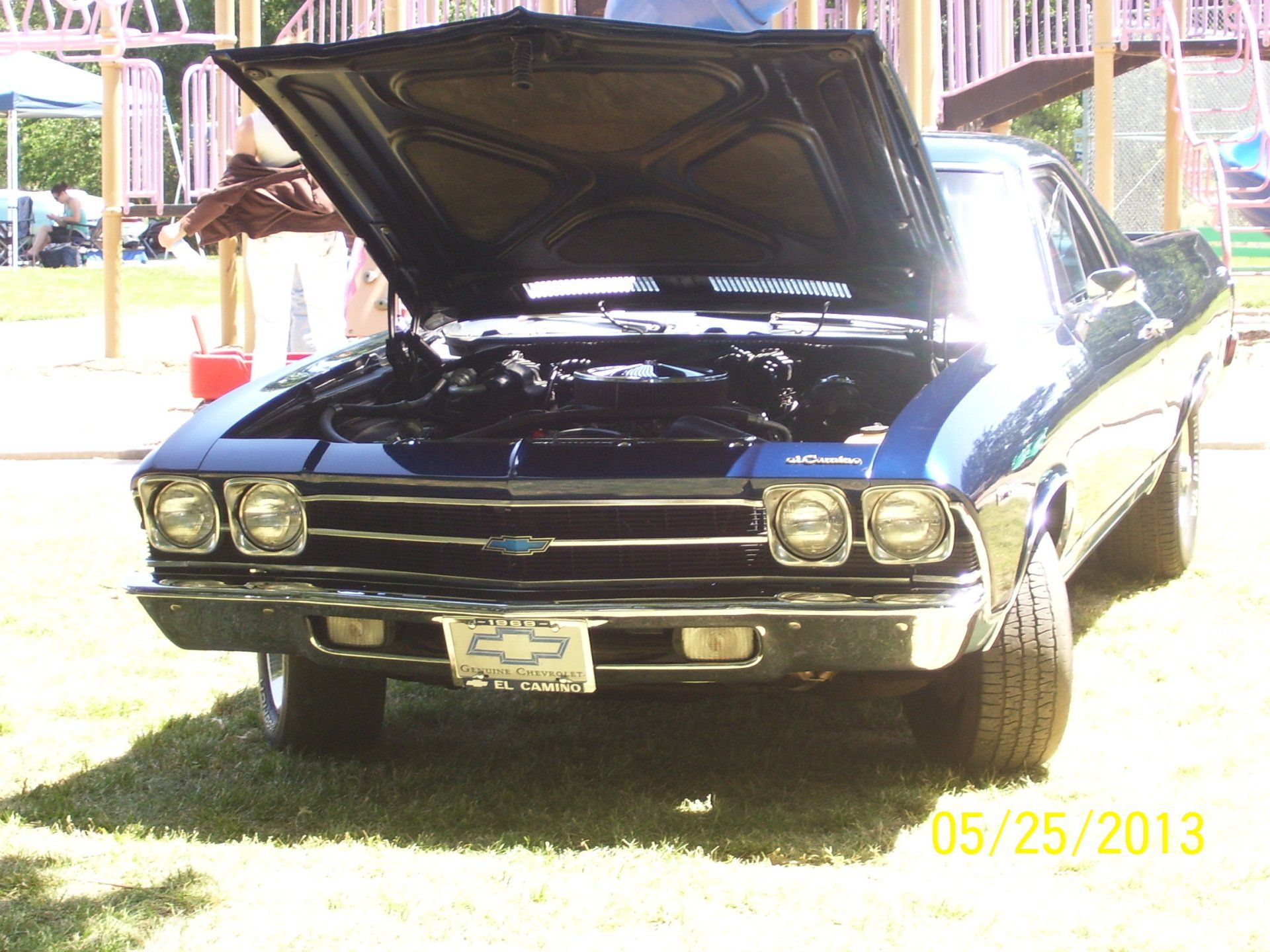 A blue chevrolet with the hood up is parked in the grass