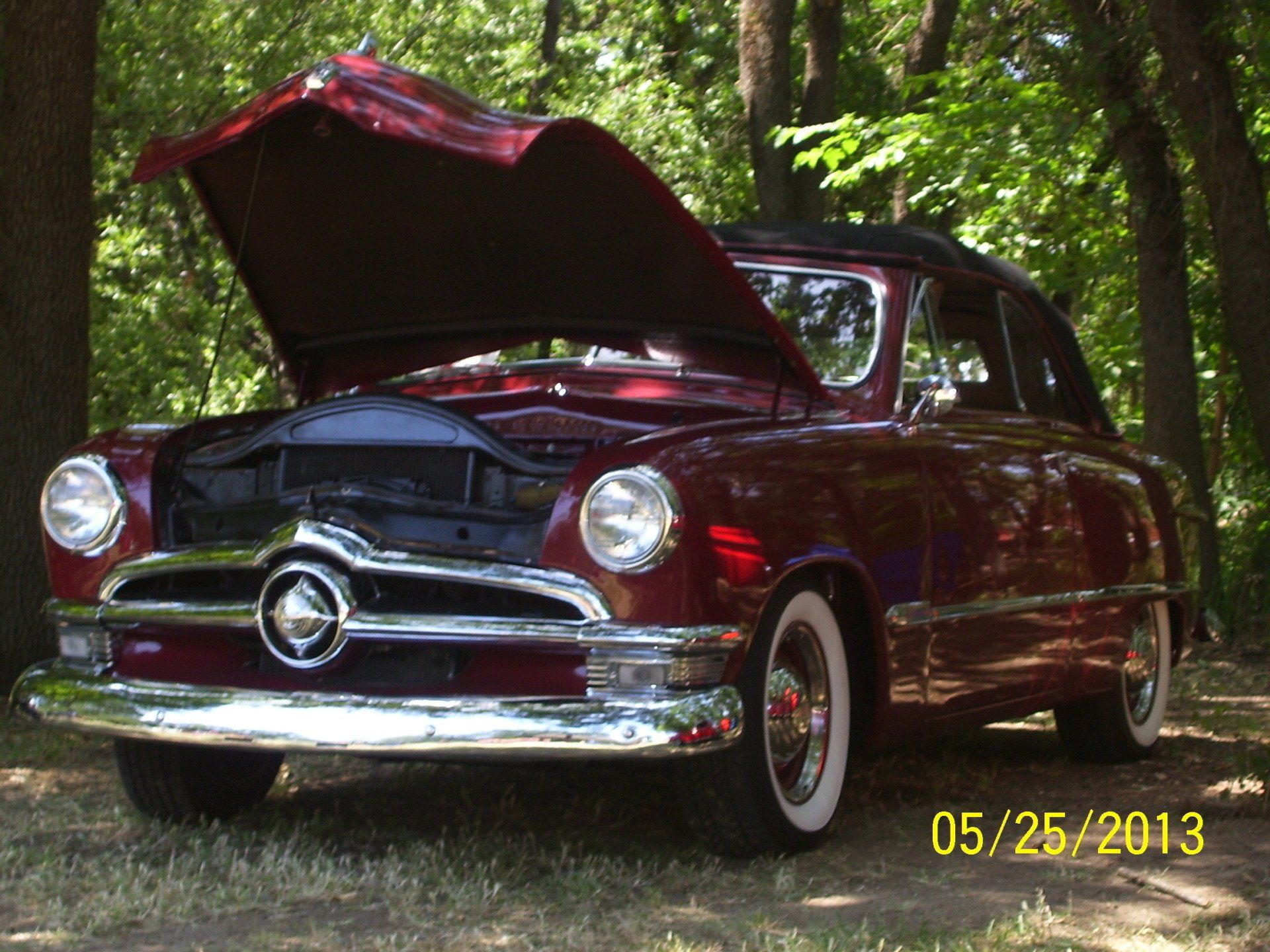 A red car with the hood up is parked in the woods on 05/25/2013