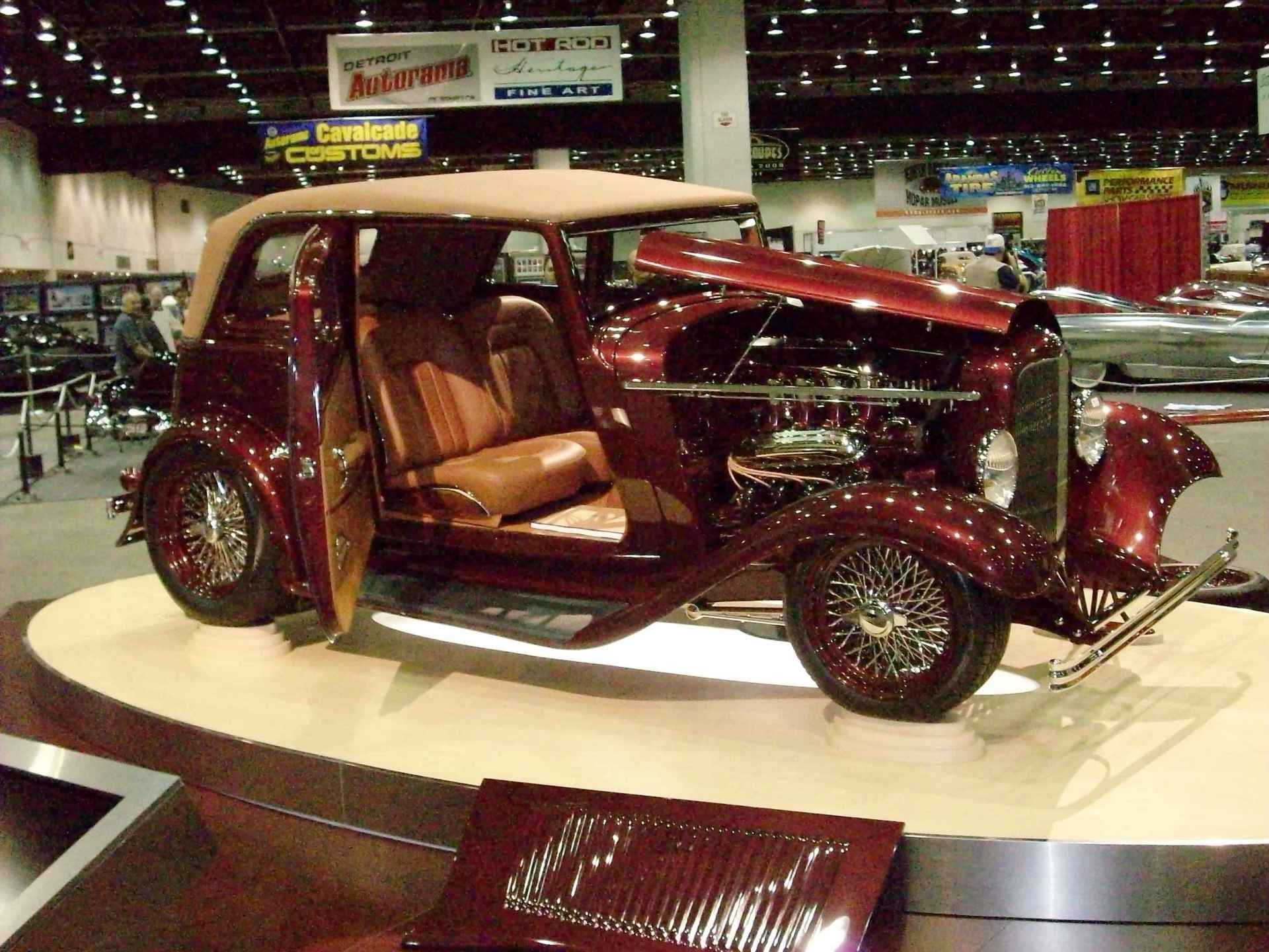 A red car with the hood open is on display at a car show