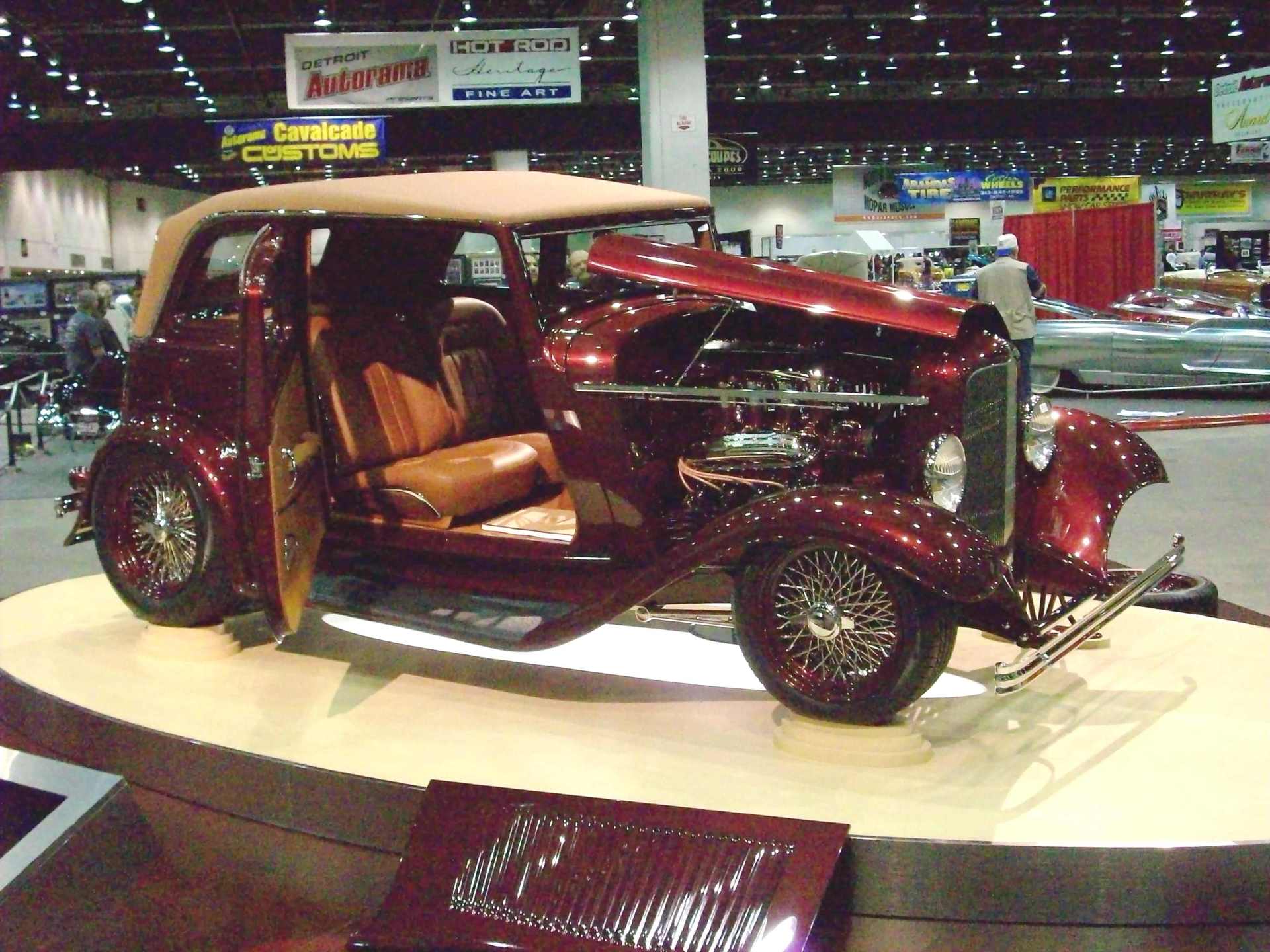 A red car with the hood open is on display at a car show