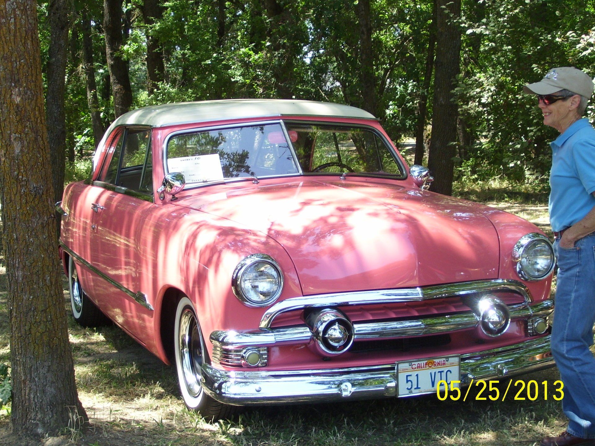 A man stands next to a pink car with a texas license plate