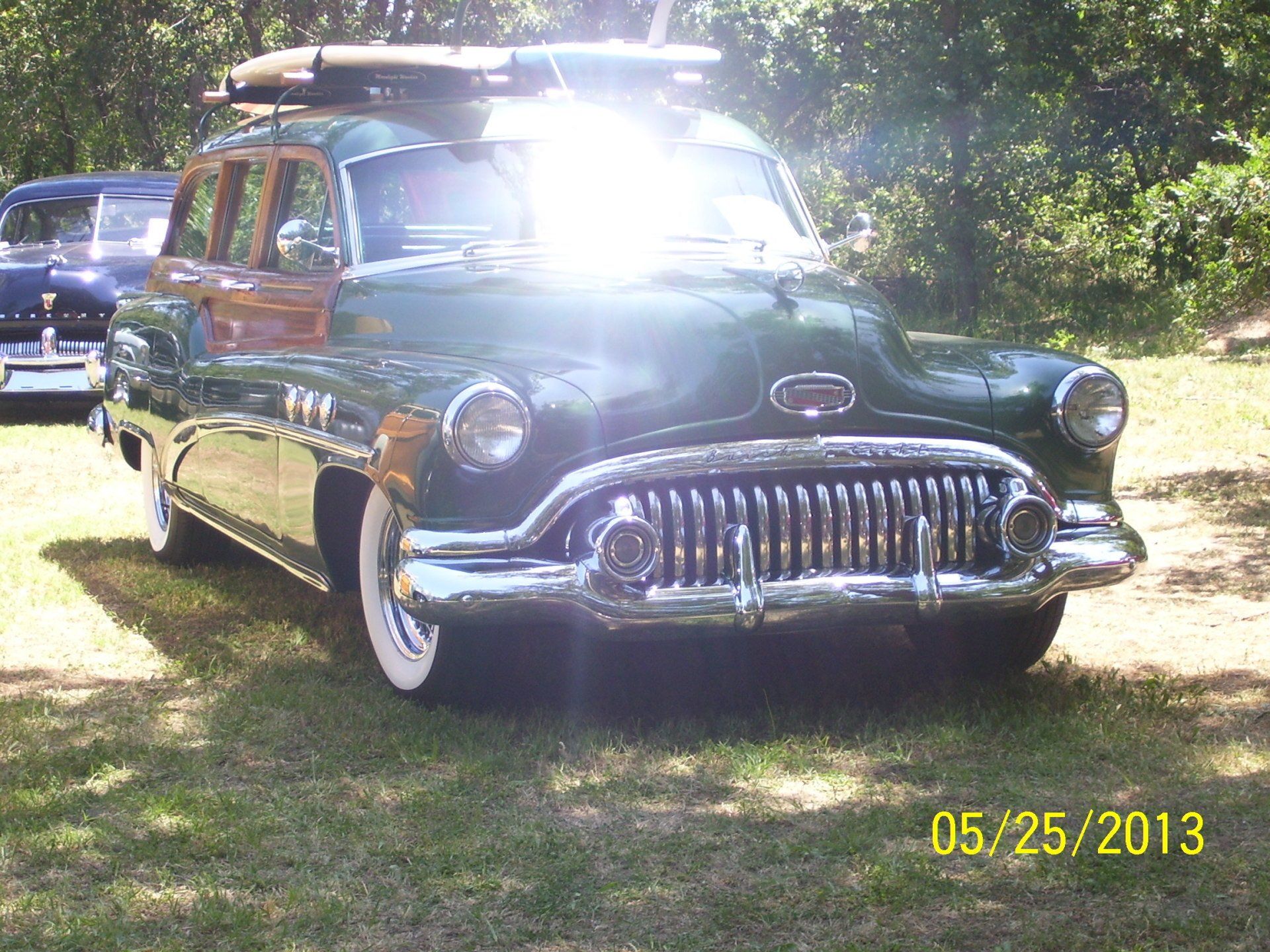 A green buick woody station wagon is parked in the grass