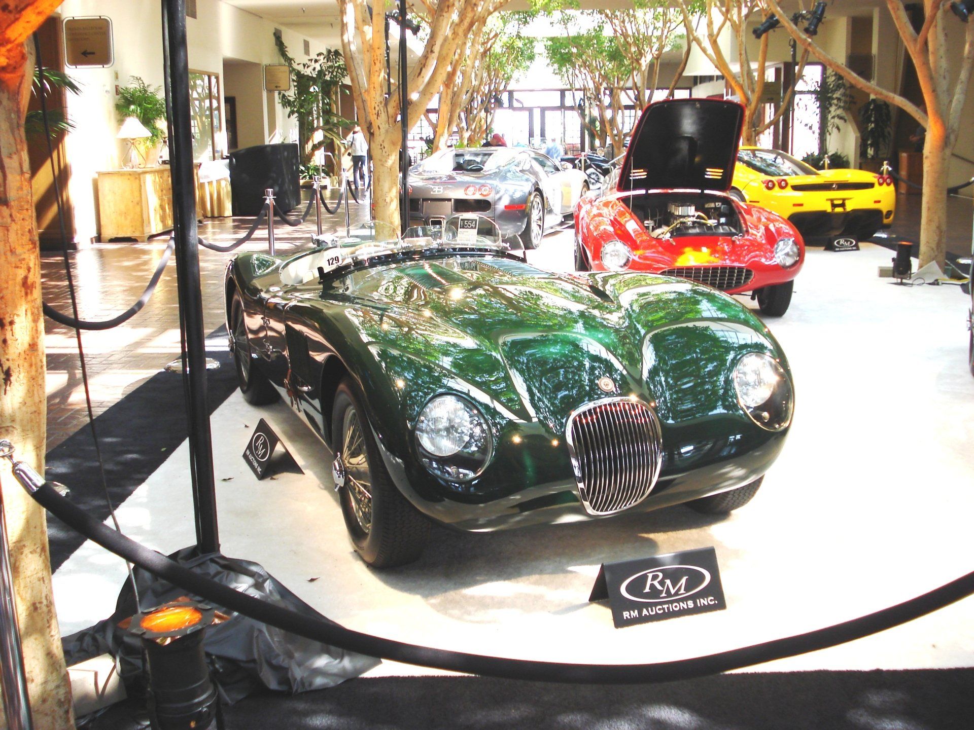 A green sports car with the hood up is on display