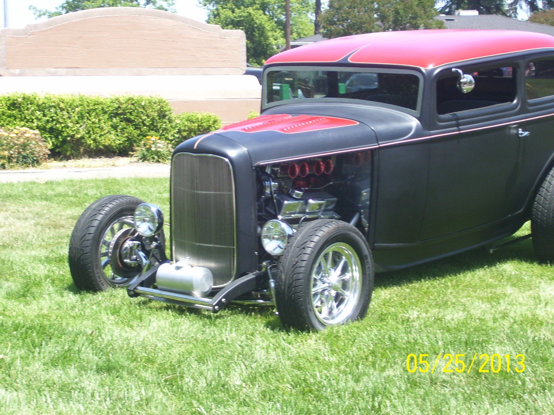 A black and red car is parked in the grass.