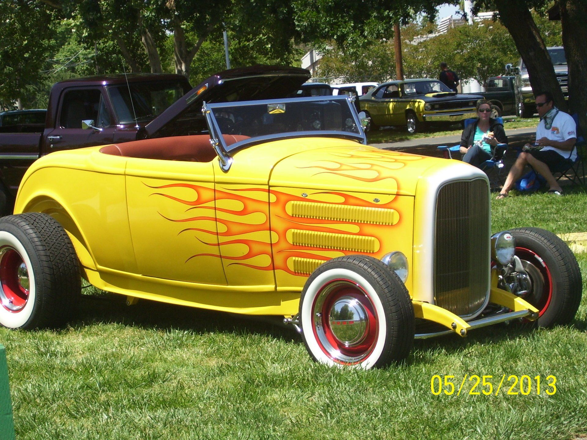 A yellow car with flames painted on it is parked in the grass
