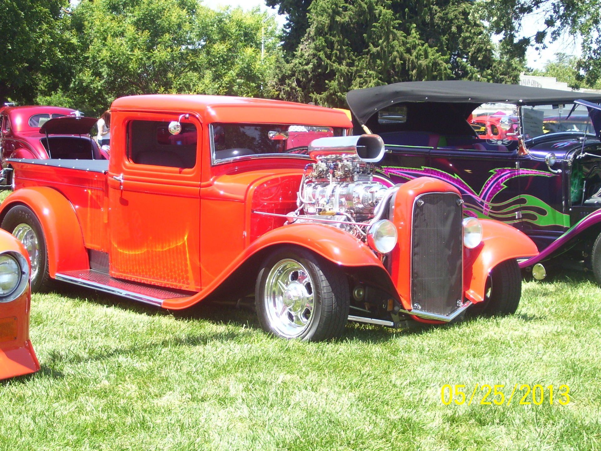 A red truck is parked next to a purple car