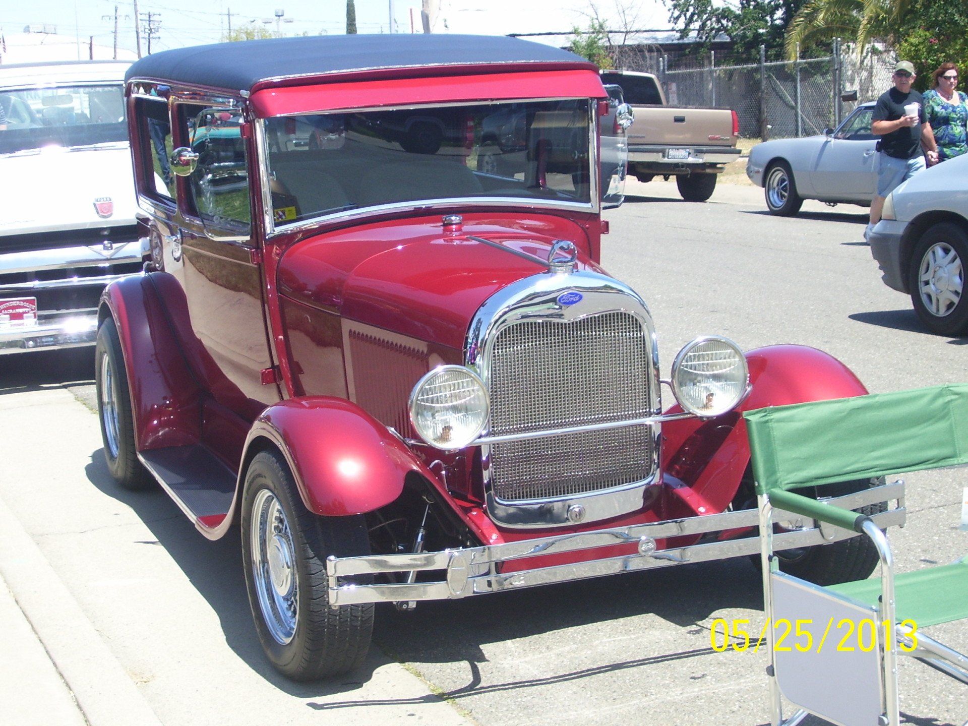 An old red car is parked on the side of the road
