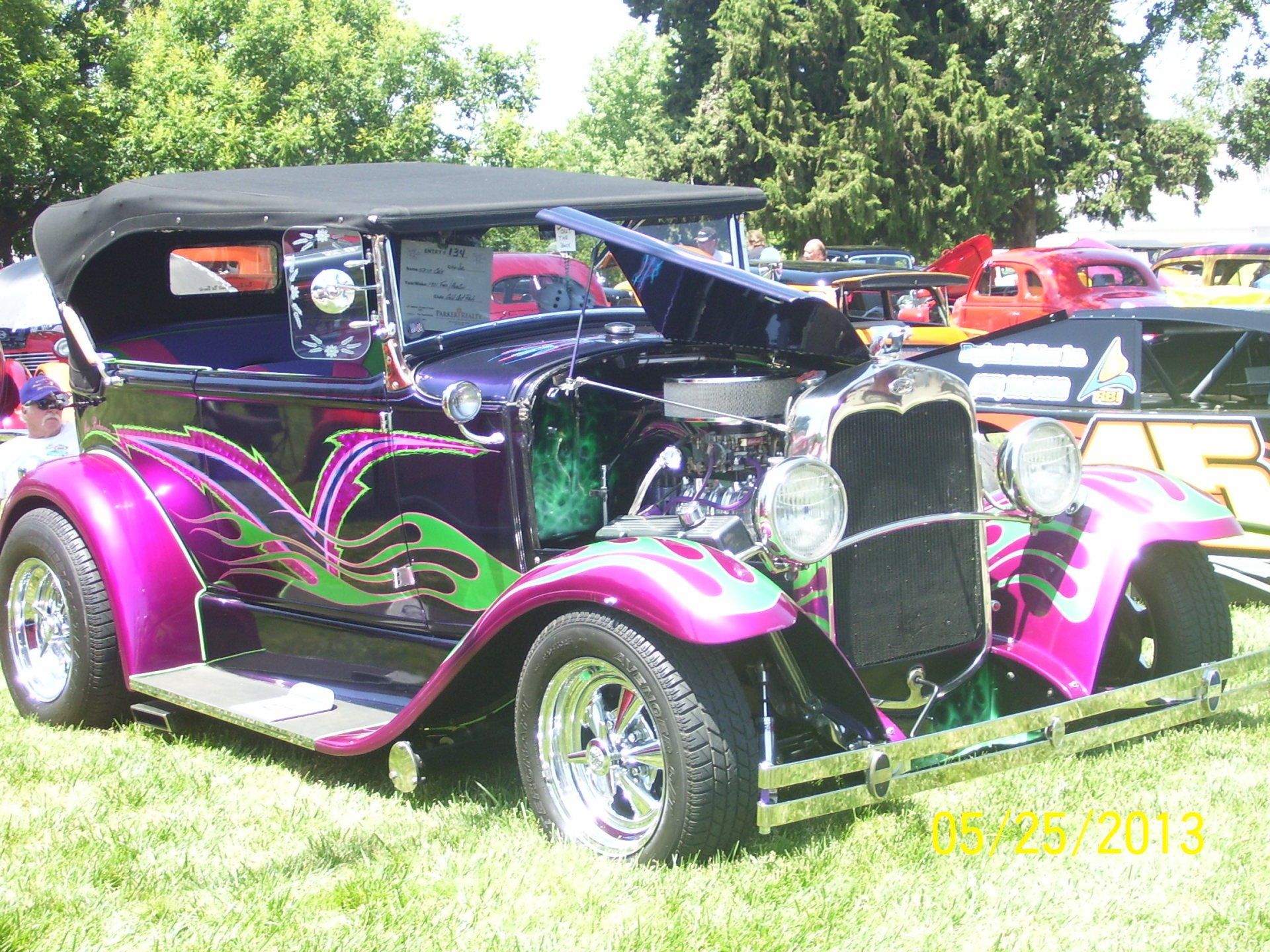 A purple car with flames painted on it is parked in the grass