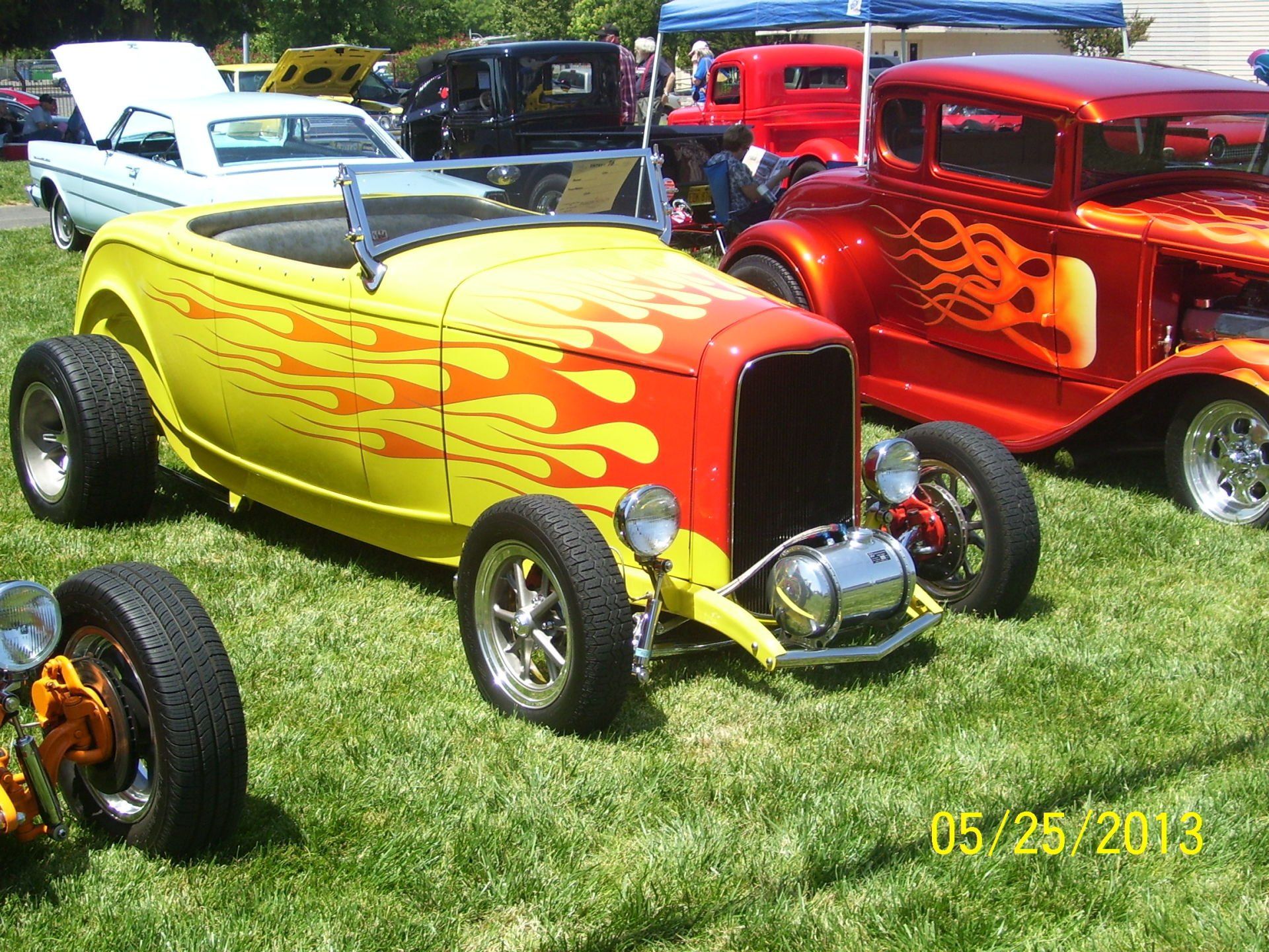A yellow car with flames painted on it is parked next to a red car