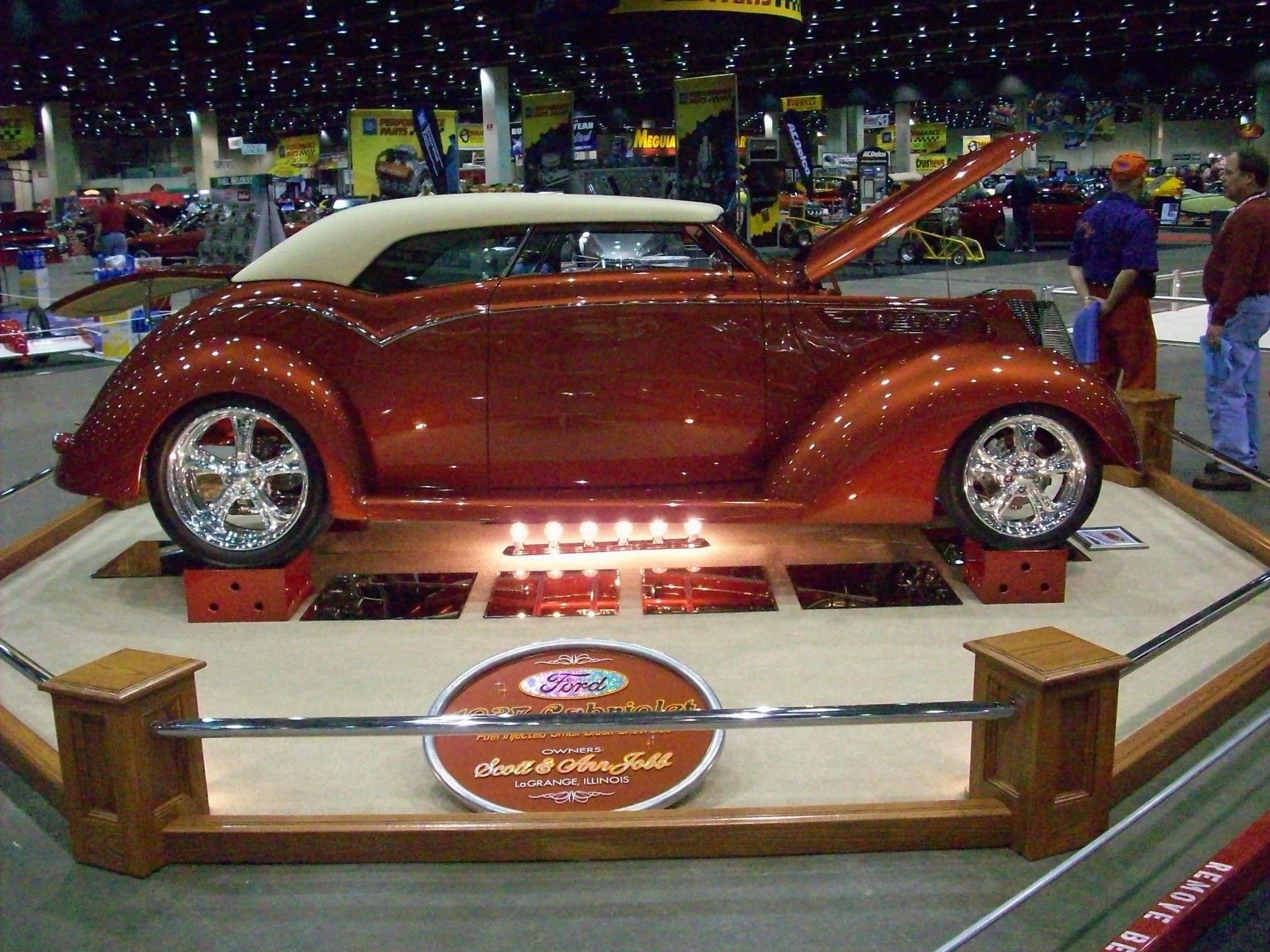 A red car with the hood up is on display at a car show