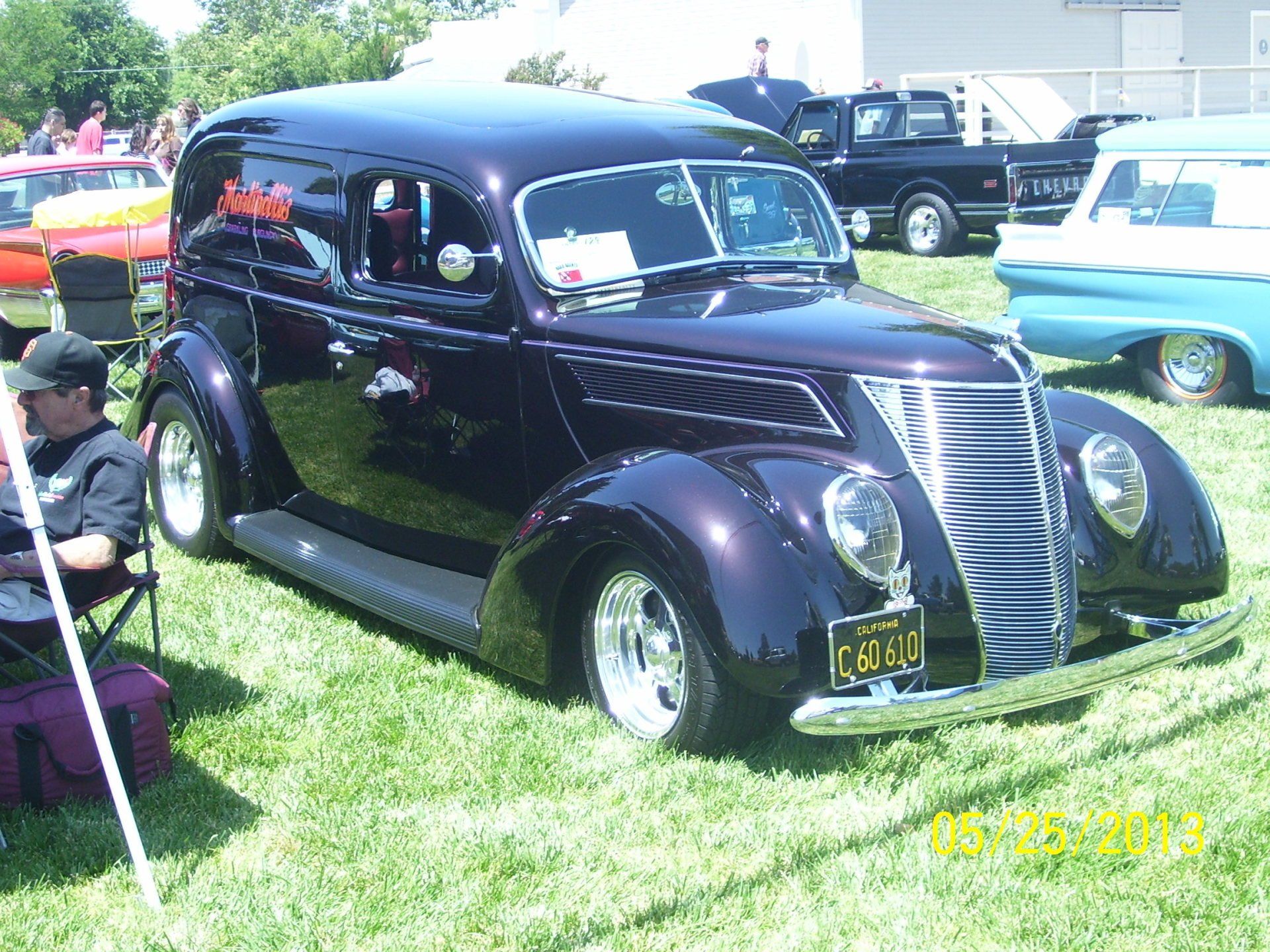 A man sits in a chair next to a purple car