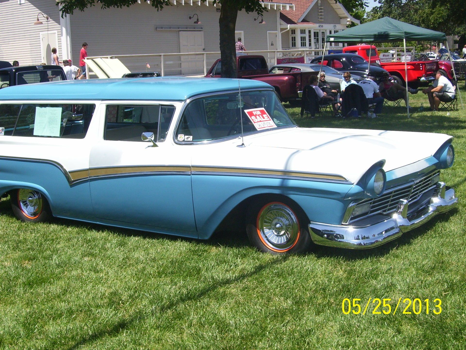 A blue and white car is parked in a grassy field