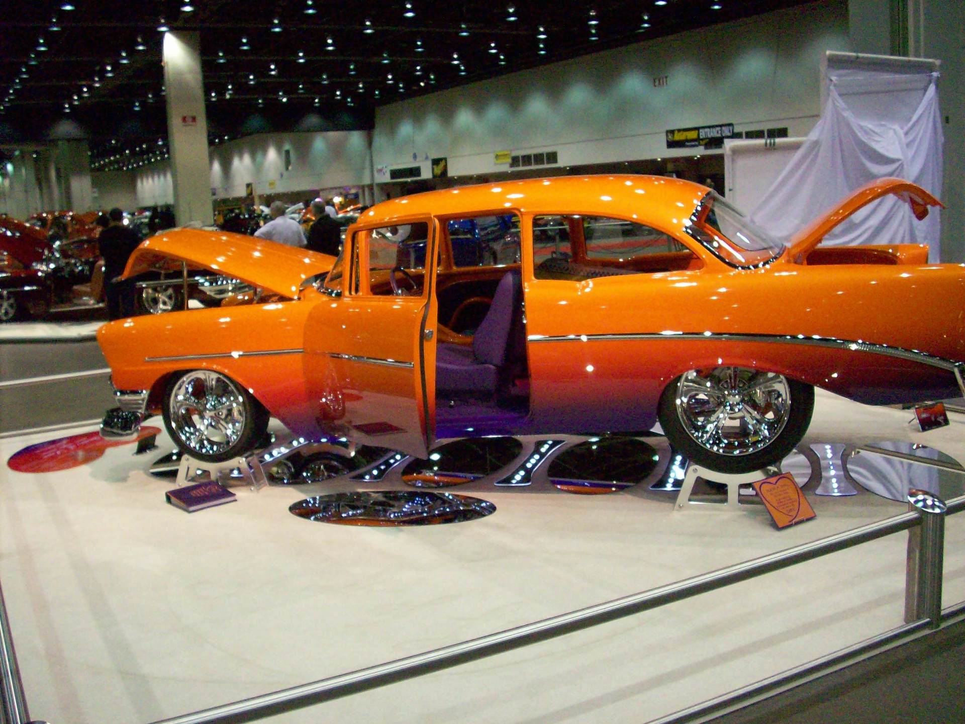 An orange and purple car is on display at a car show