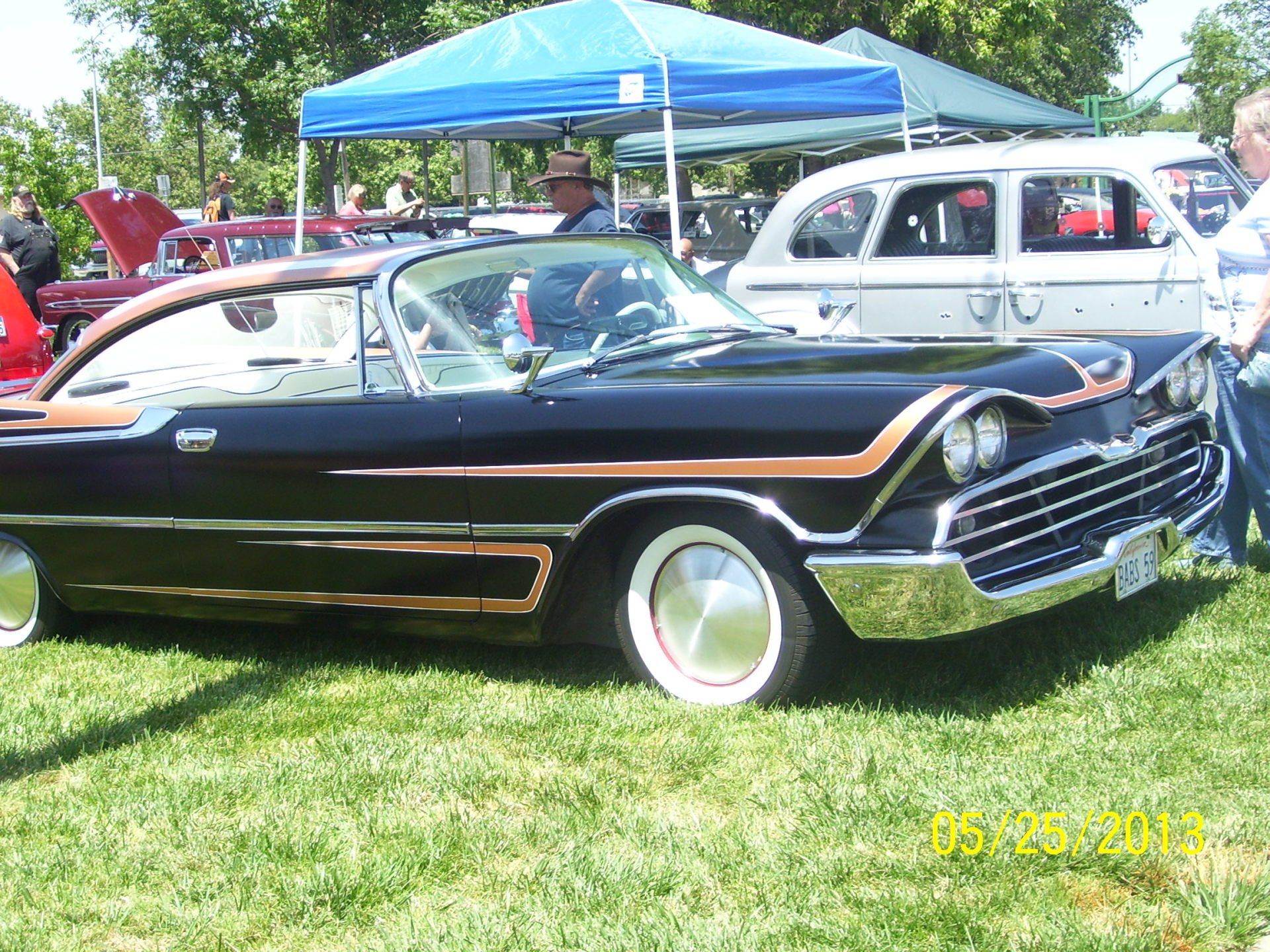 A black car is parked in the grass at a car show