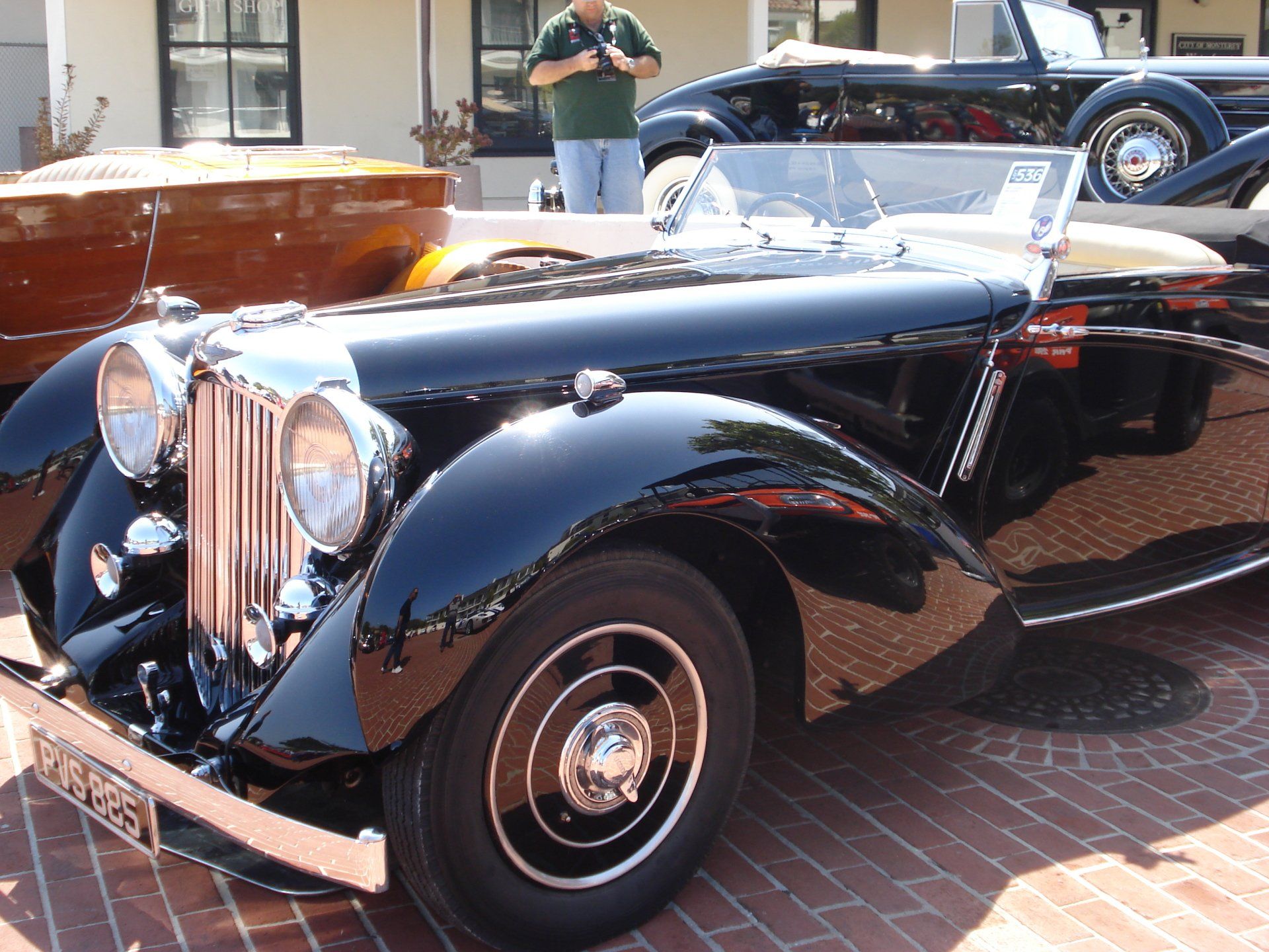 A man is taking a picture of a black car