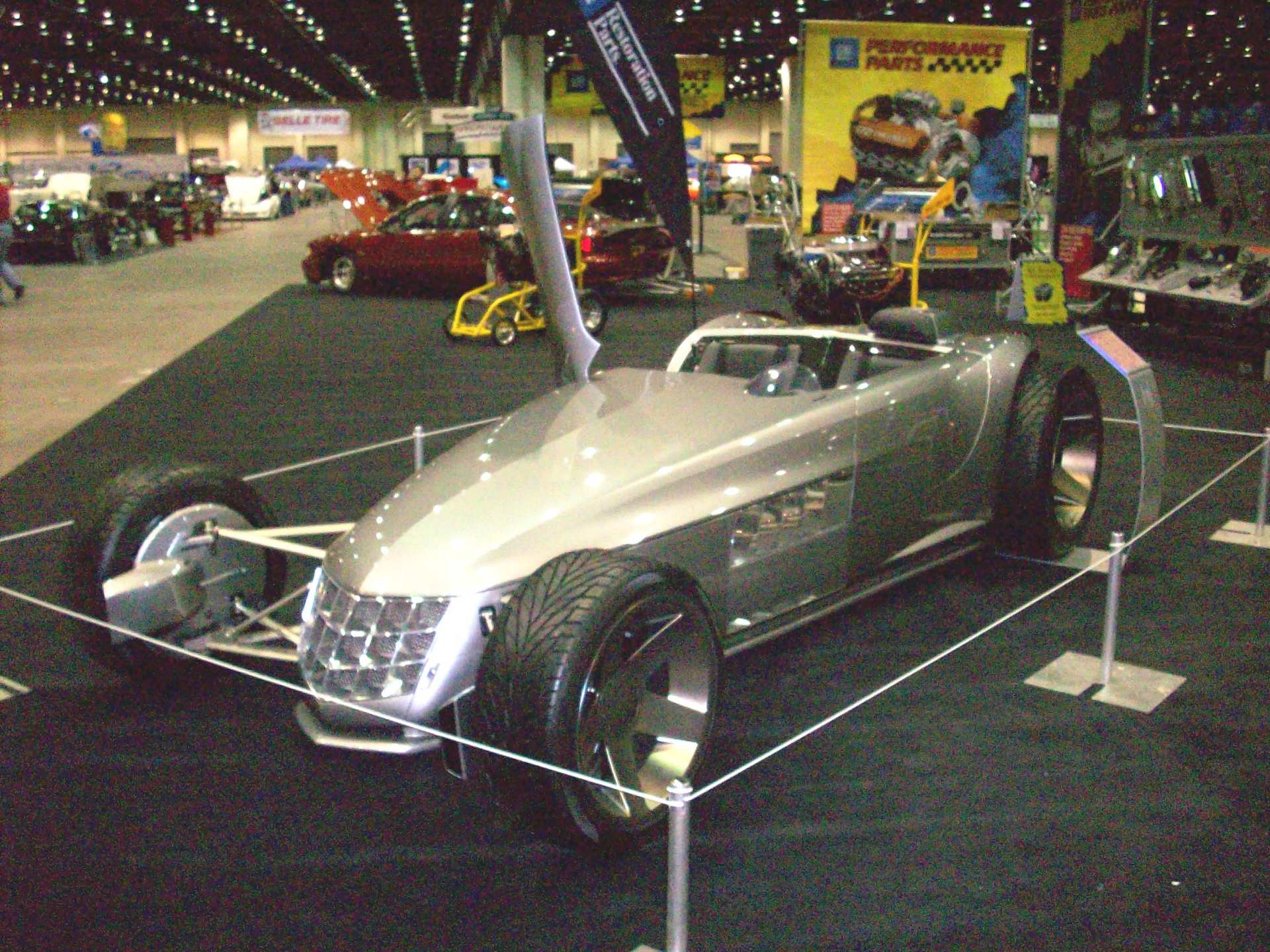A silver car is on display at a car show