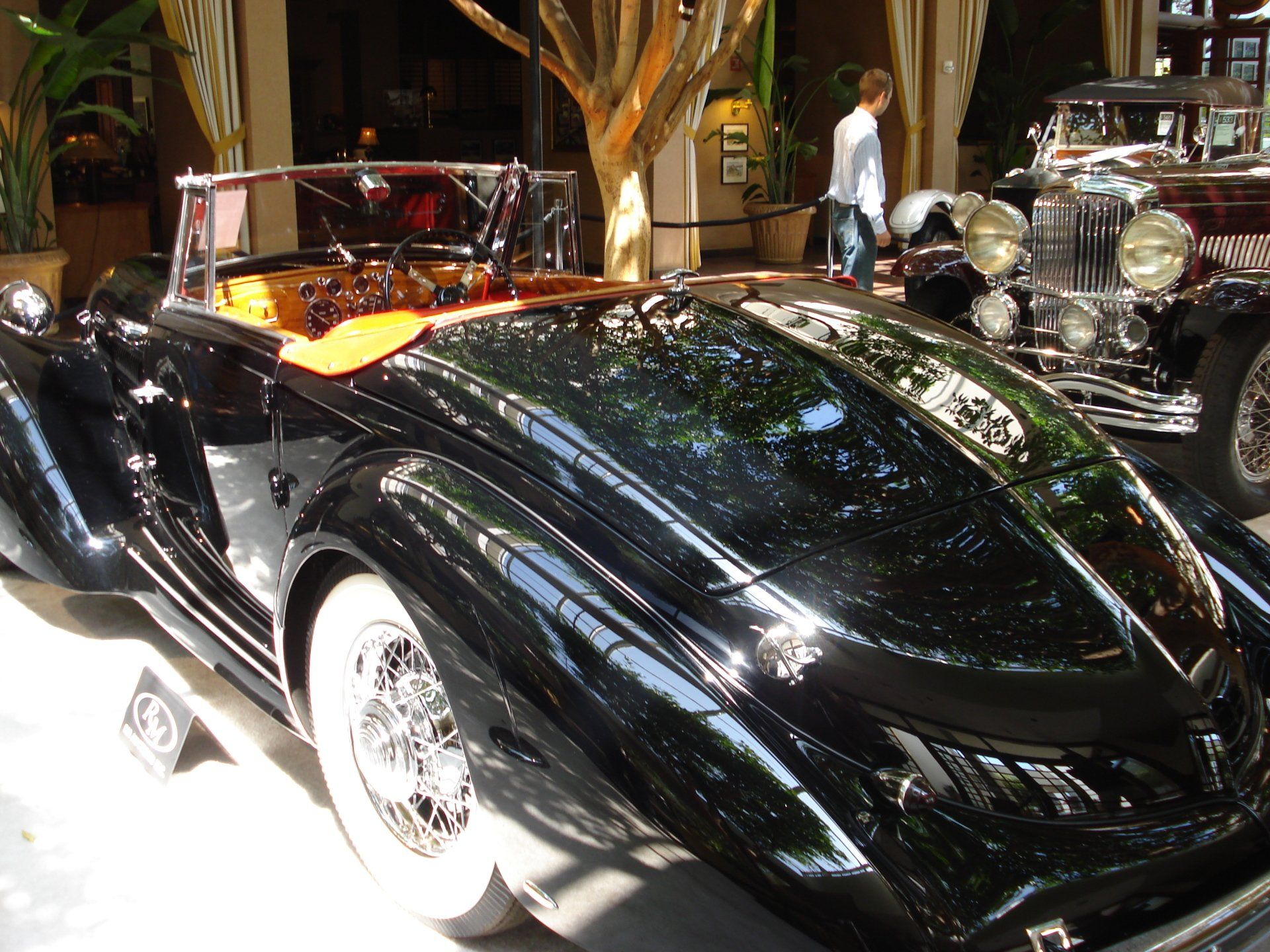 A black car with white tires is parked in front of a building