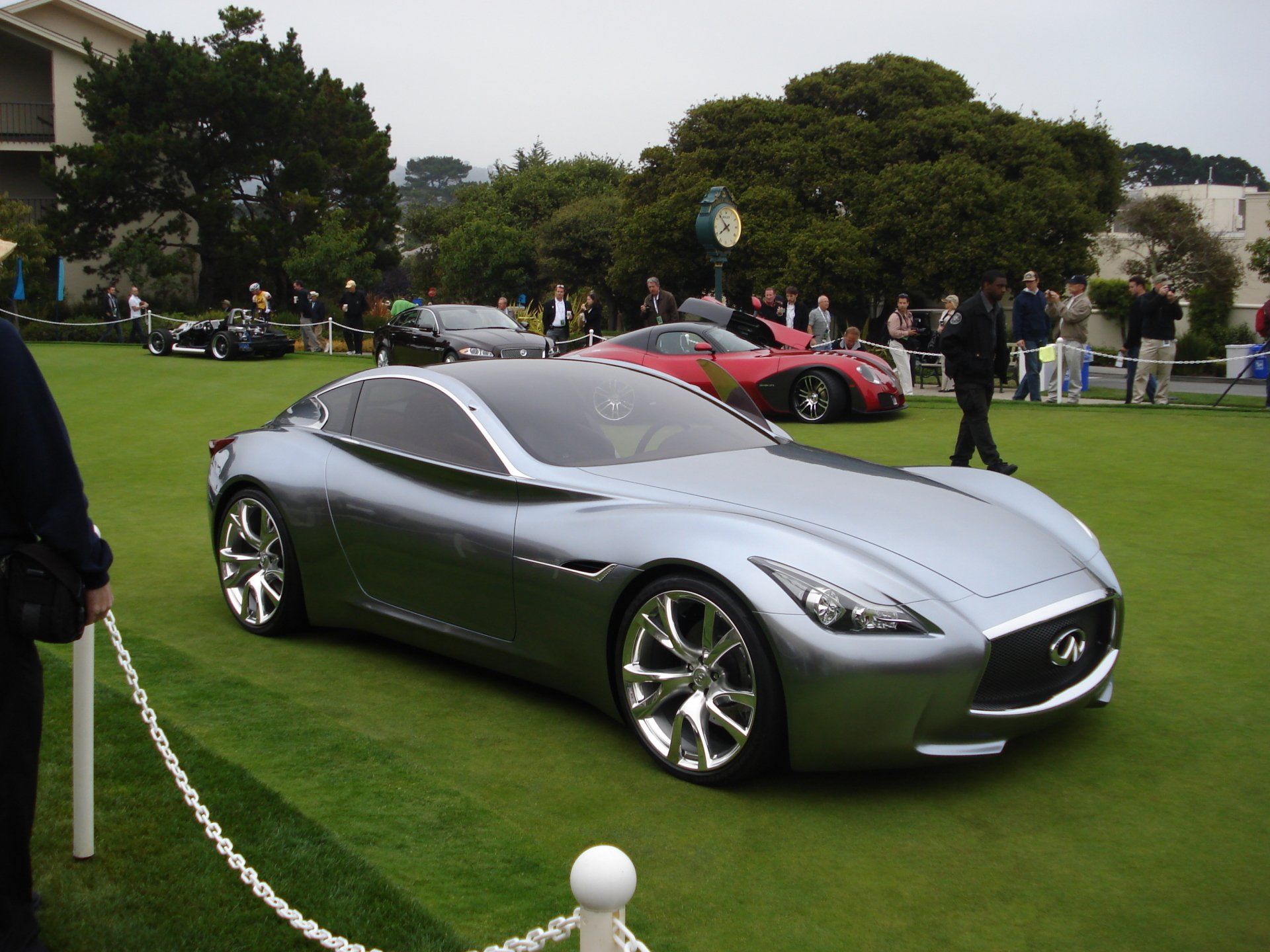 A silver sports car is parked on a grassy field