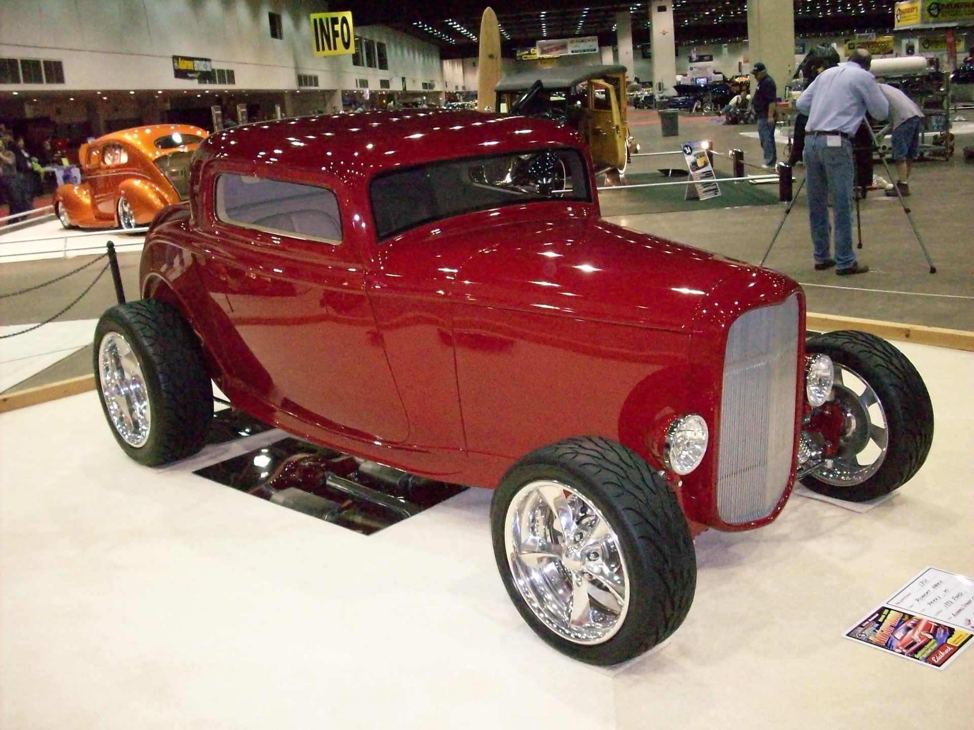 A red hot rod is on display at a car show