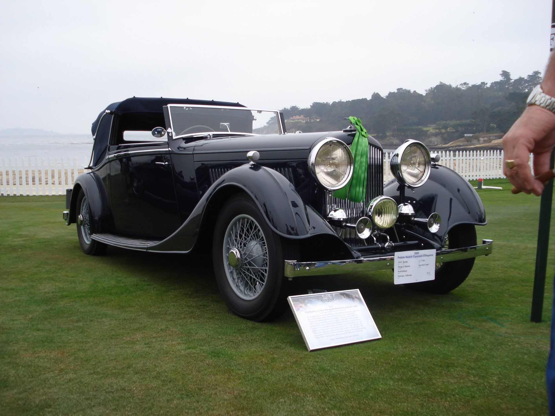 A black car is parked on a lush green field