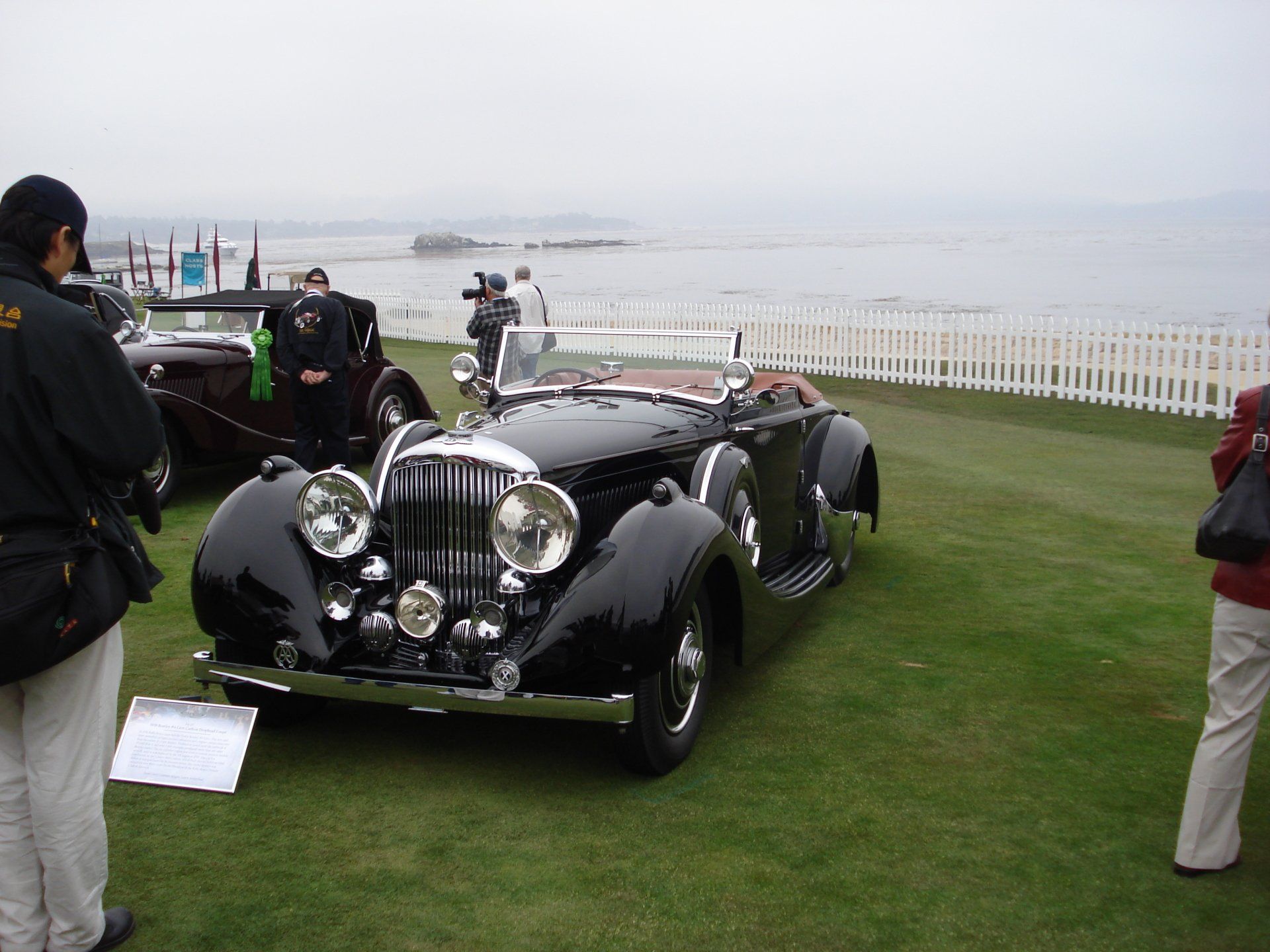 A man is taking a picture of a black car