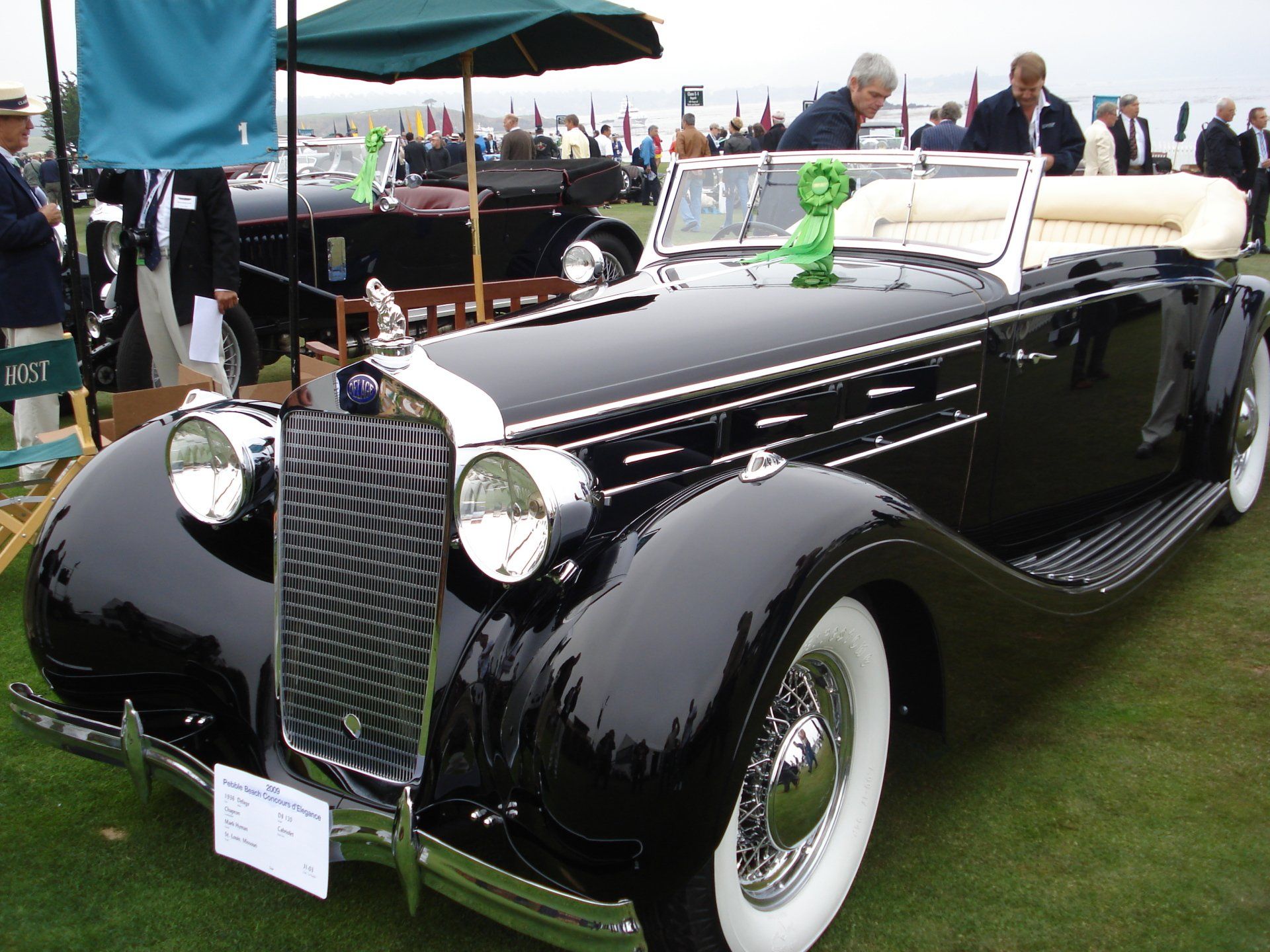 A black car with white tires is parked on the grass