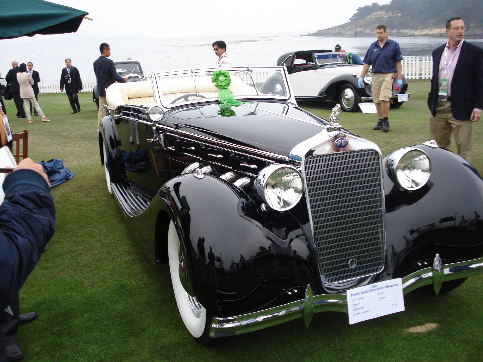 A black car with white tires is parked on the grass