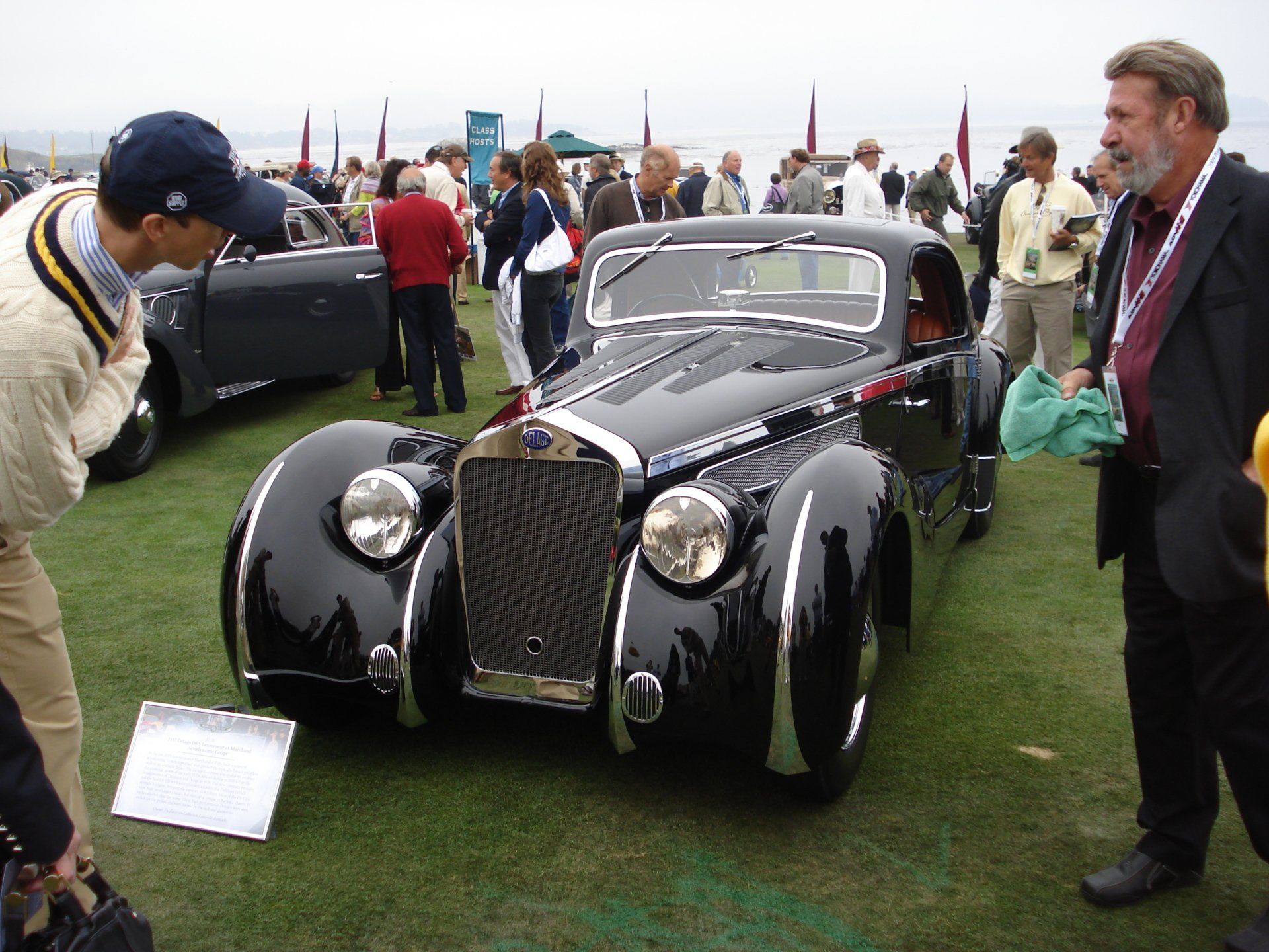 A group of people are standing around a black car
