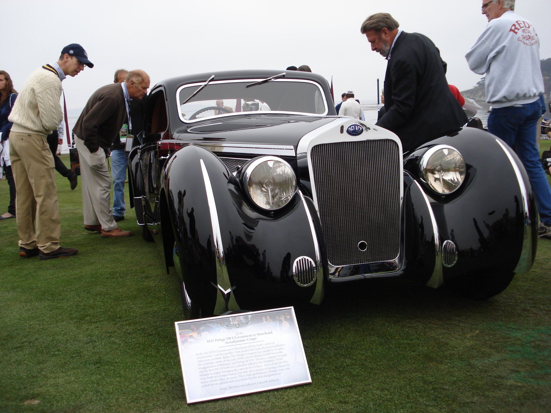 A group of people are looking at a black car