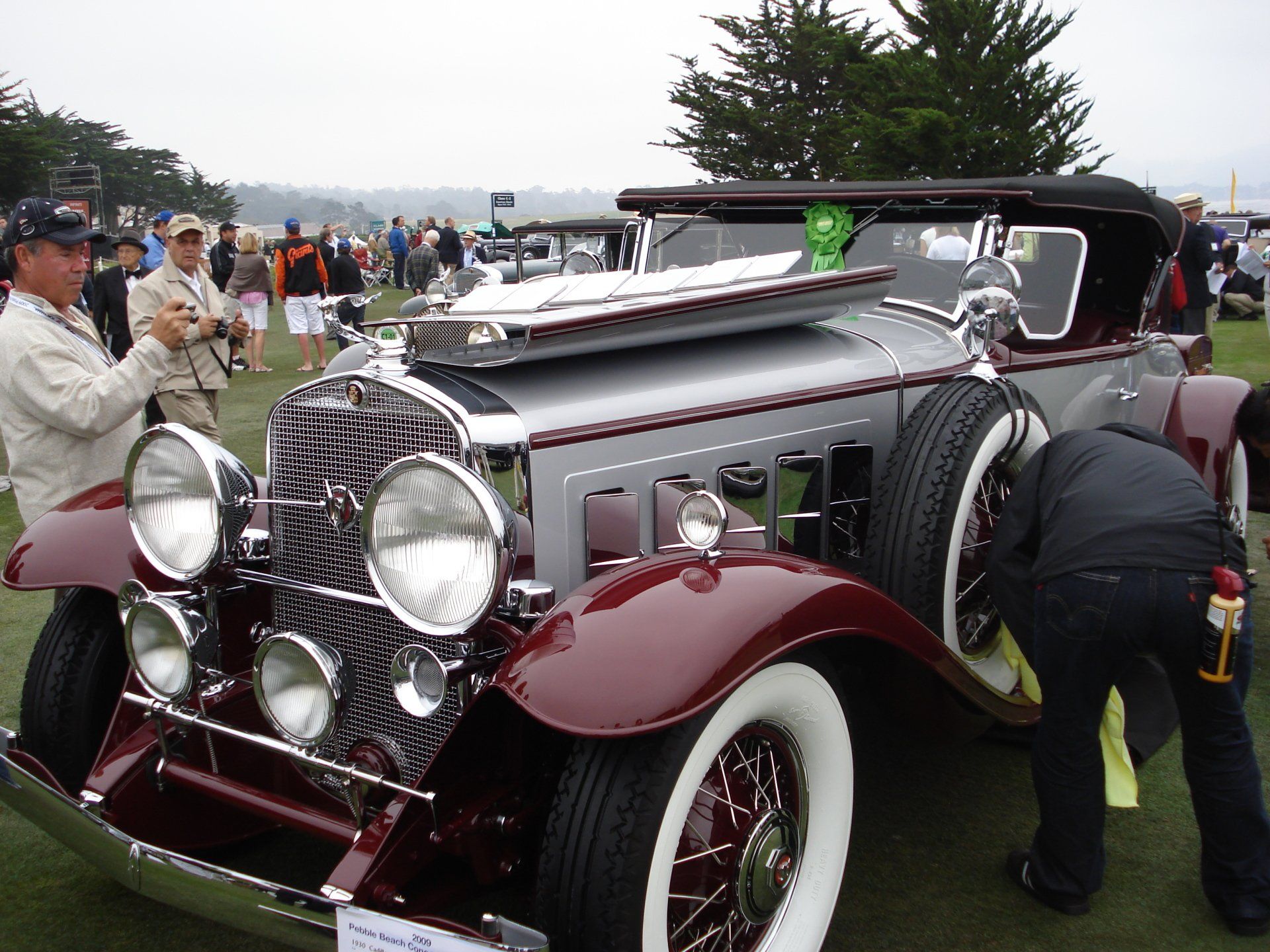 A group of people are looking at an old fashioned car