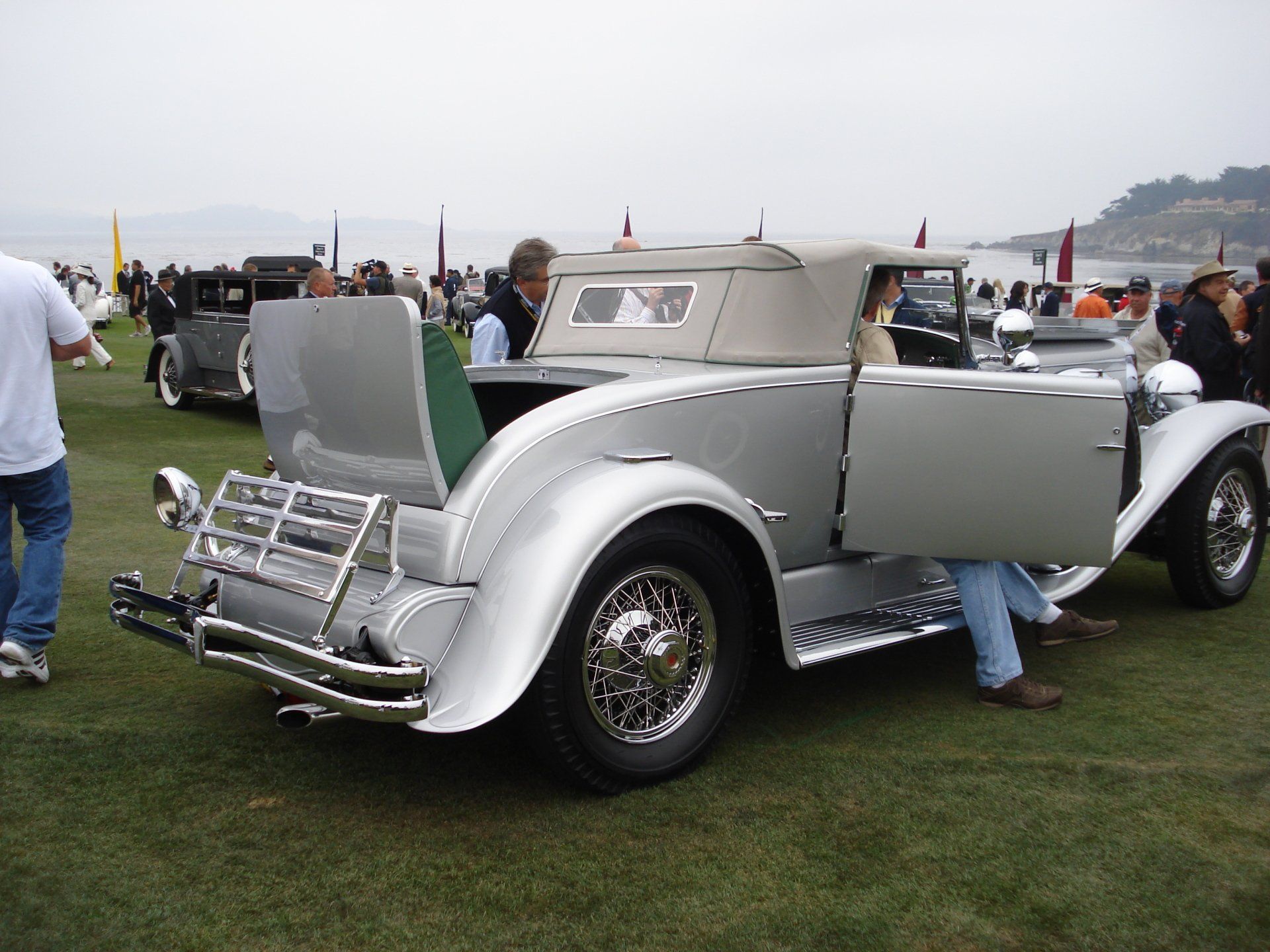 A silver car with its doors open is parked in the grass