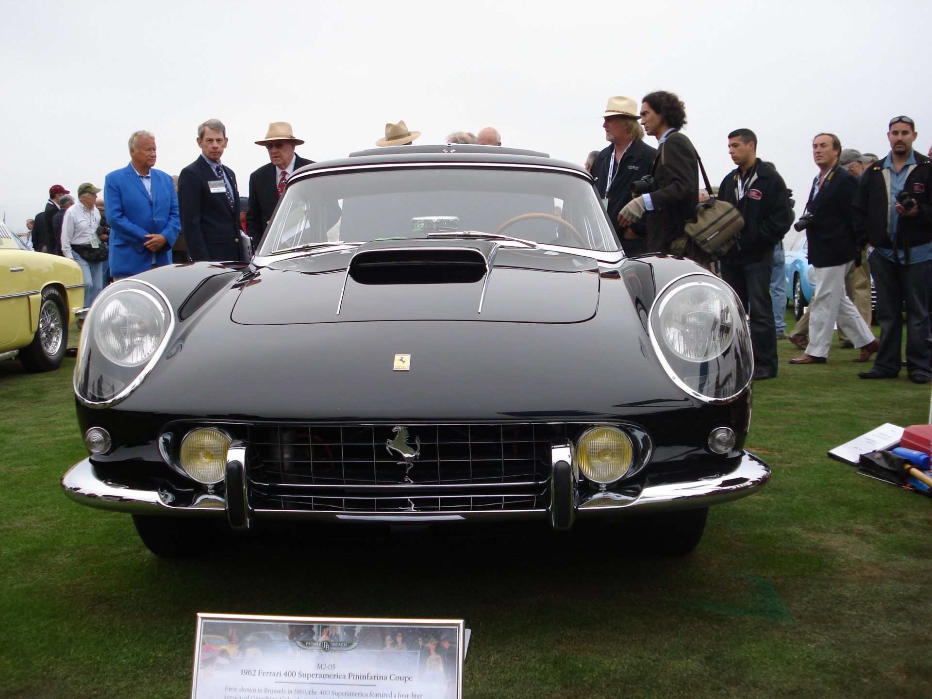 A group of people are standing around a black ferrari