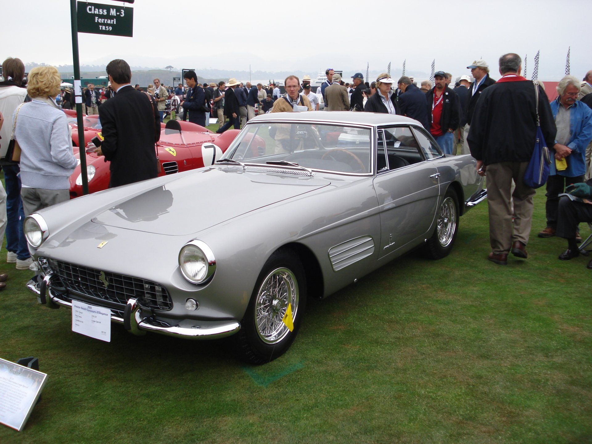 A group of people are standing around a silver car