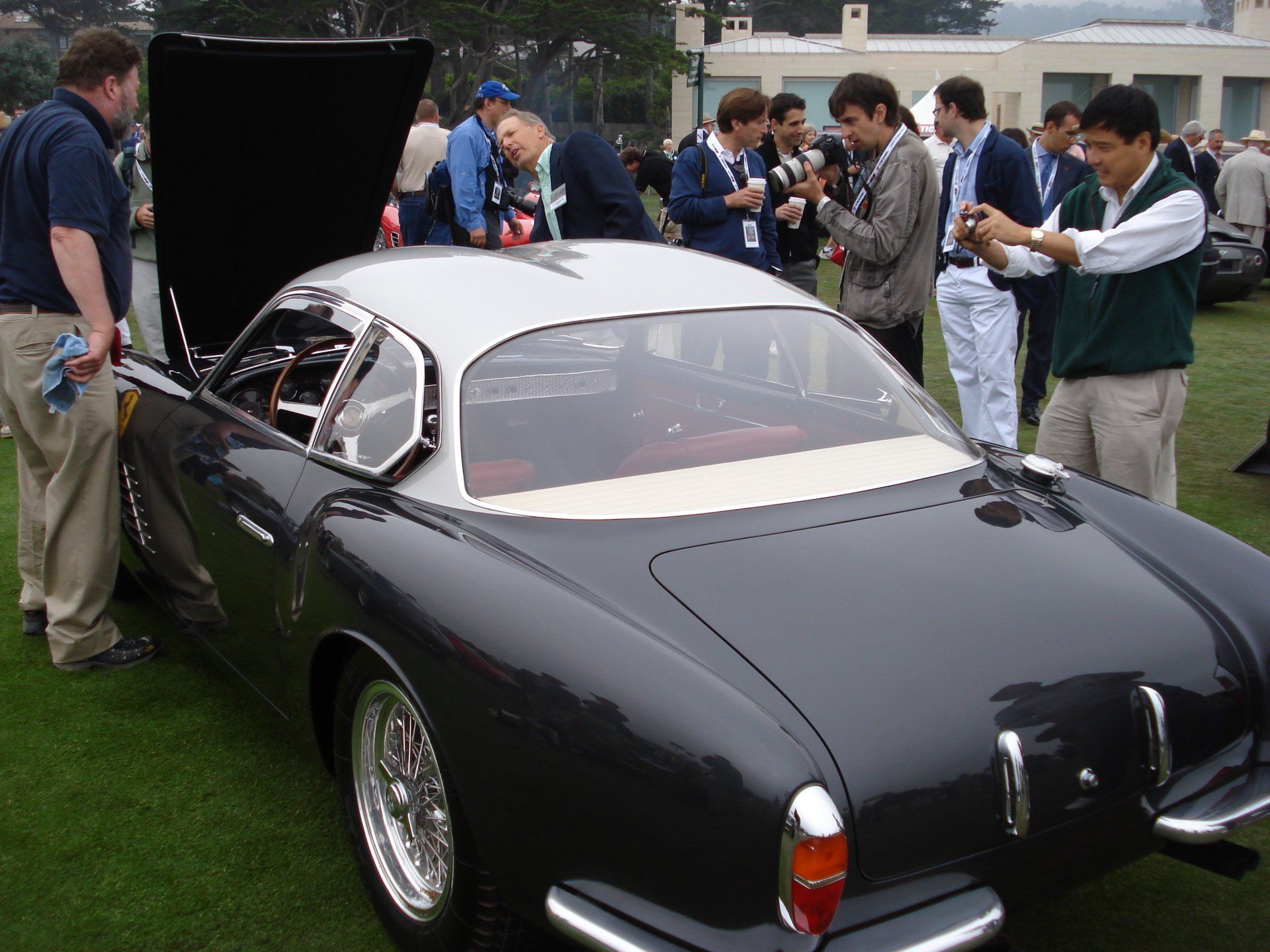 A group of men are standing around a black car with the hood up
