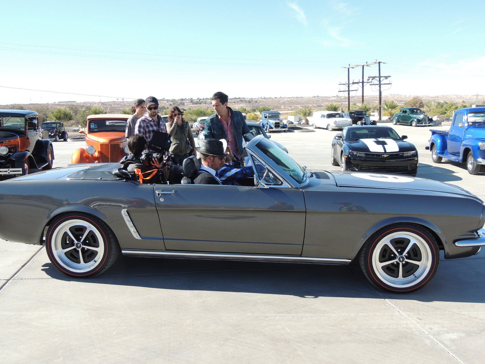 A group of people are standing around a convertible car.