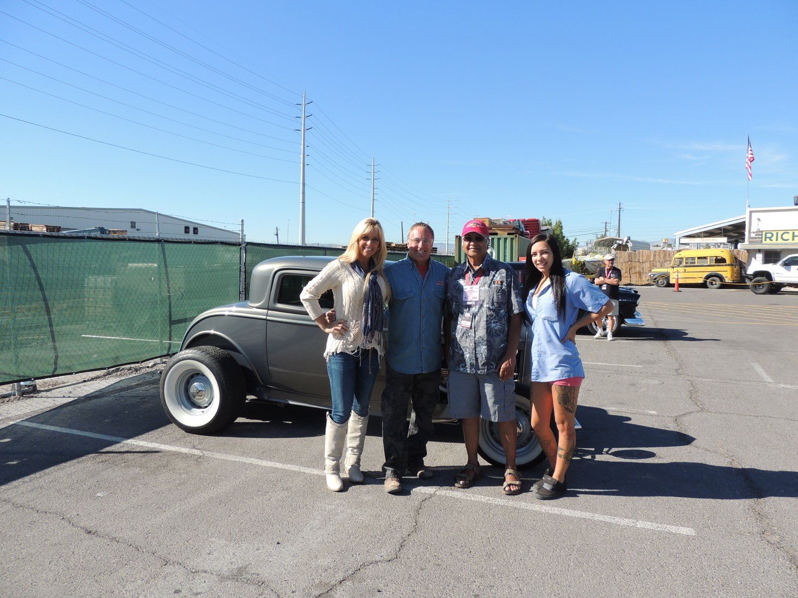 A group of people standing in front of a car in a parking lot.